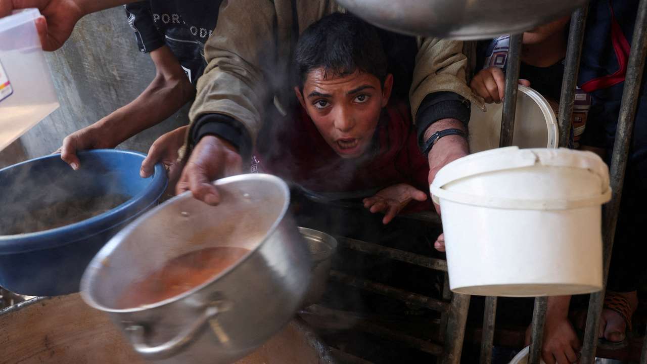 FILE PHOTO: Palestinians gather to get their share of charity food offered by volunteers, amid food shortages, in Rafah