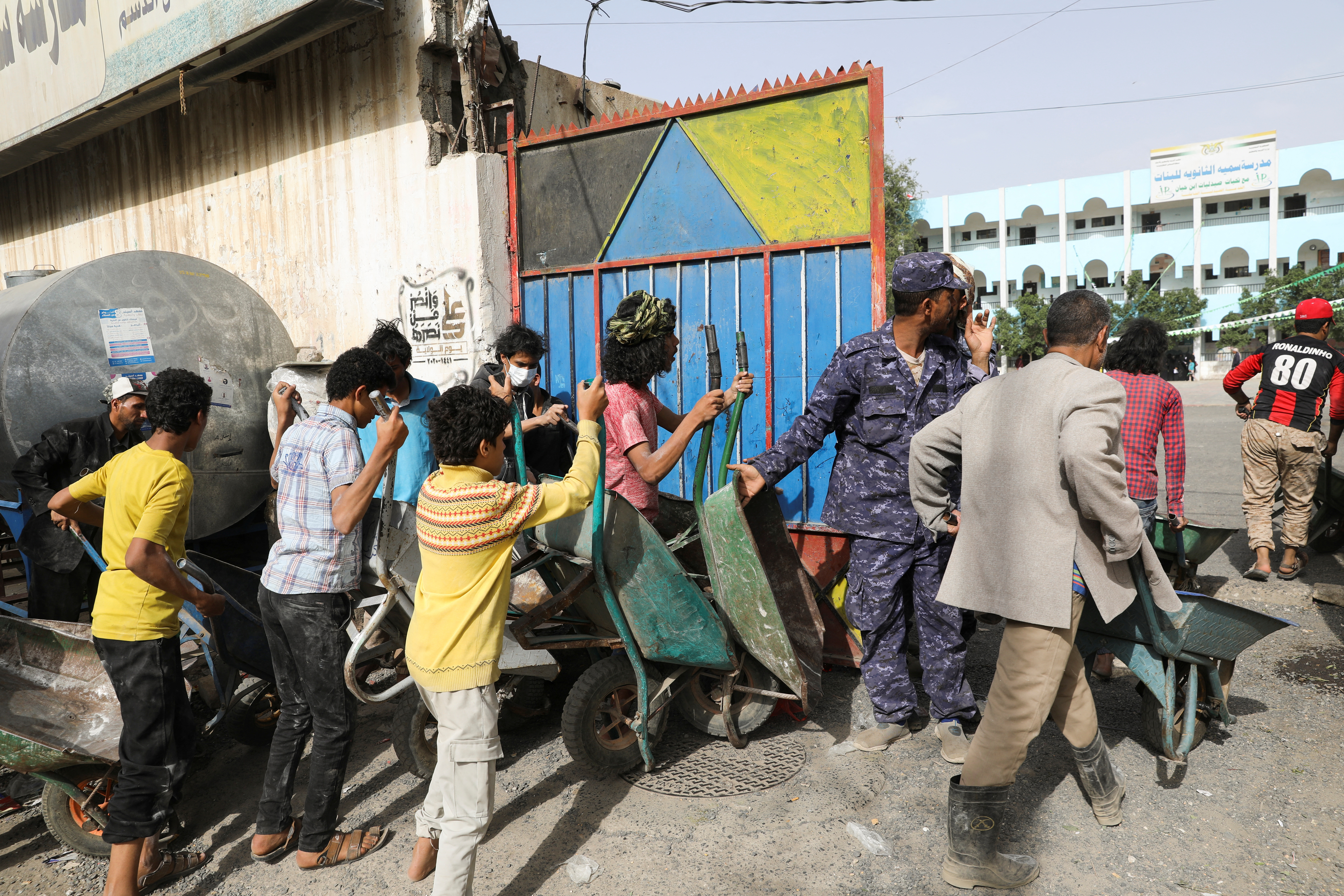 FILE PHOTO: Workers wait to ferry foodstuff outside an aid distribution center in Sanaa