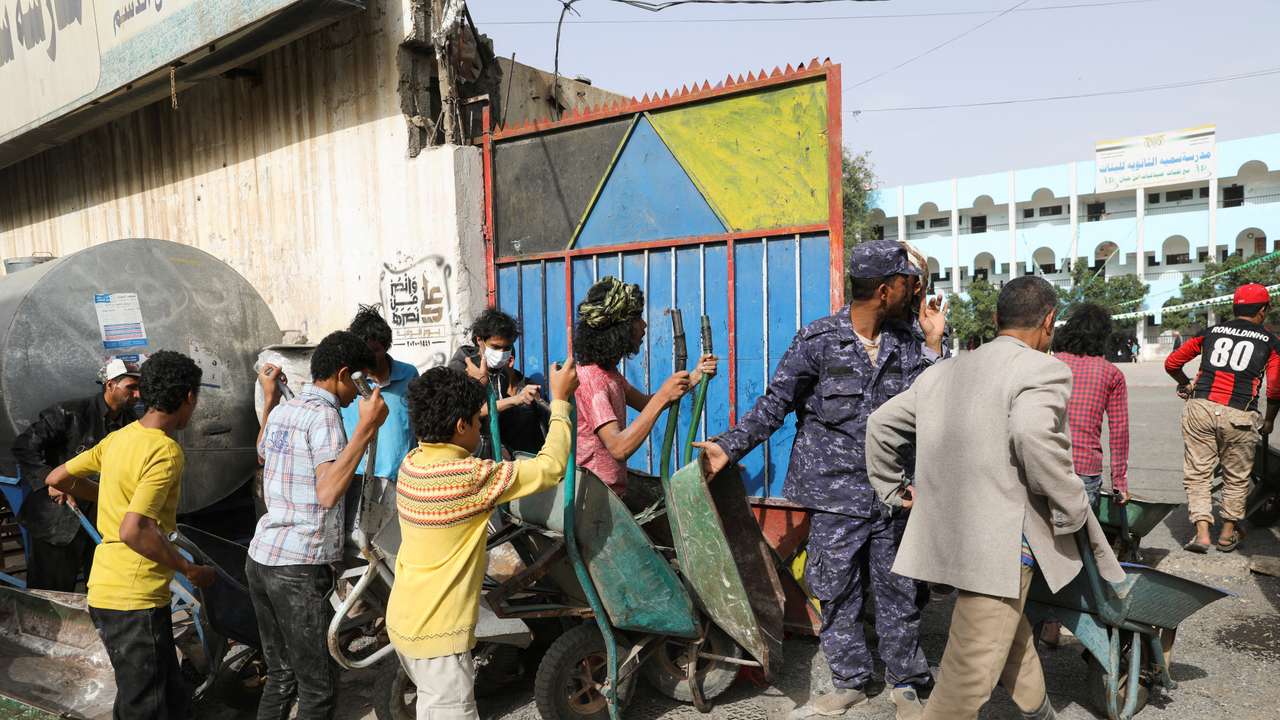 FILE PHOTO: Workers wait to ferry foodstuff outside an aid distribution center in Sanaa