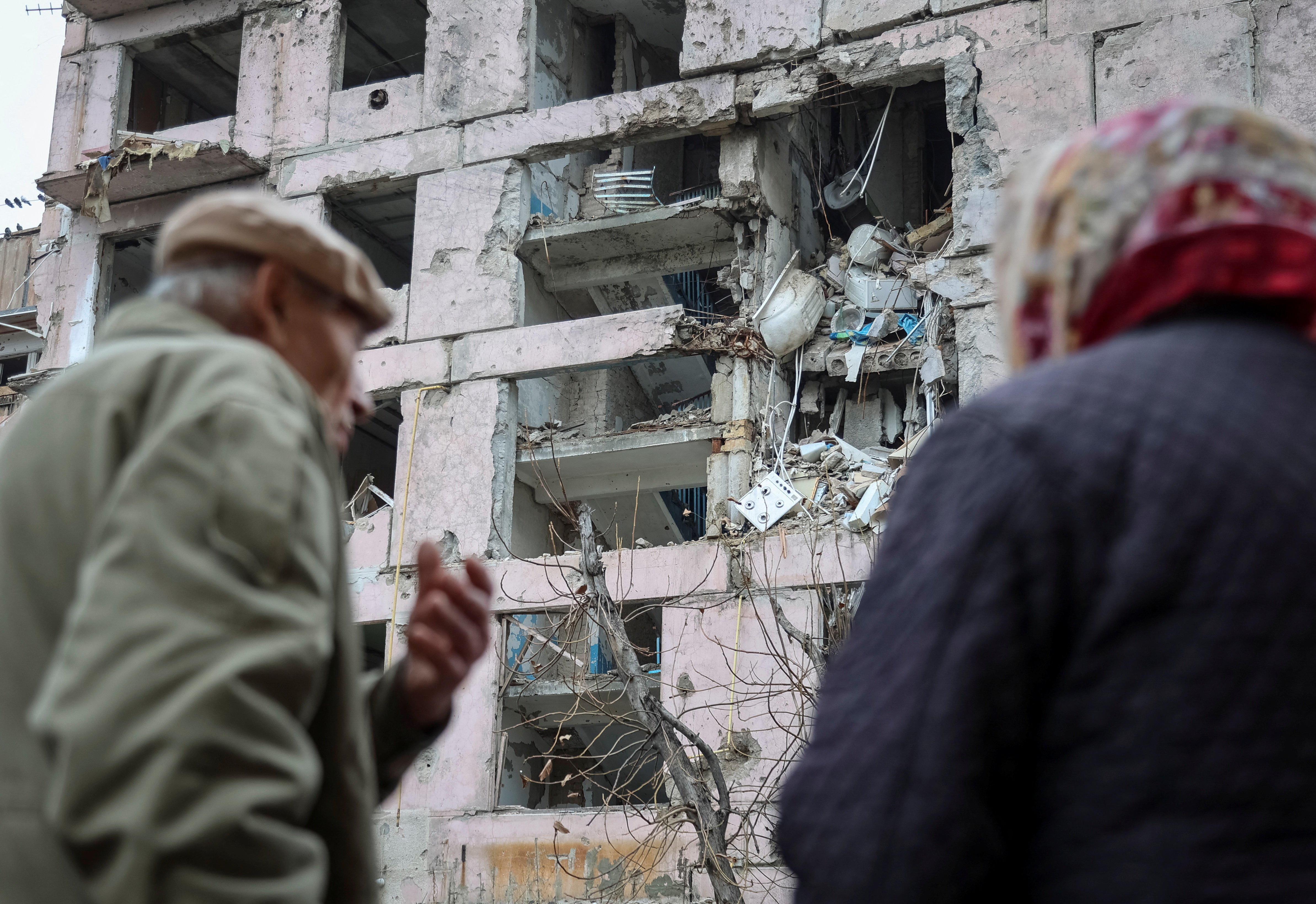 Residents stand near an apartment building hit during the Russian military strike in the frontline town of Huliaipole