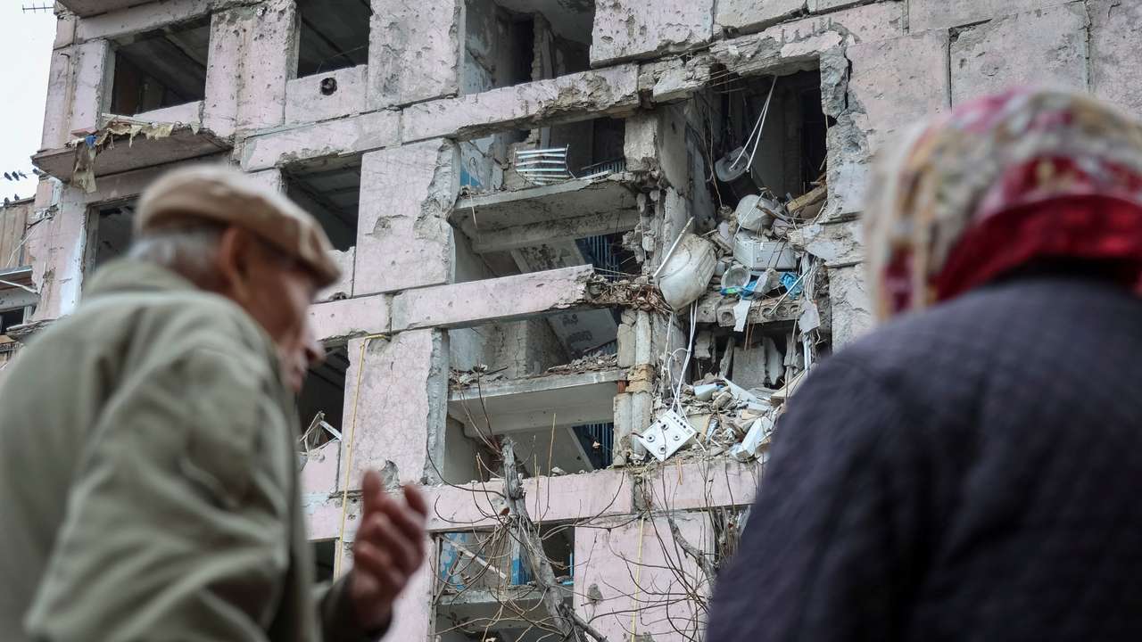Residents stand near an apartment building hit during the Russian military strike in the frontline town of Huliaipole
