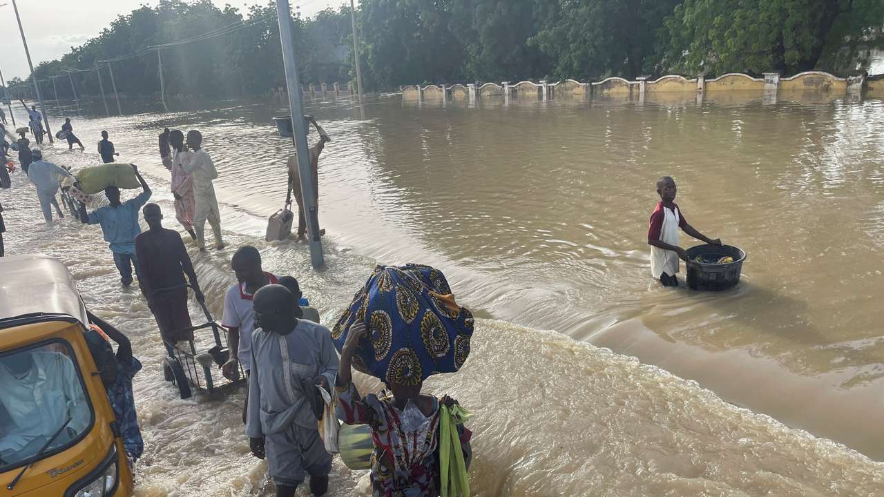Residents leave the flooded areas with their belongings in Maiduguri