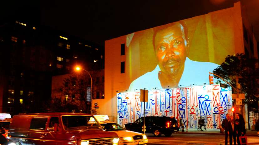 Passersby walk under a projection that is part of the non-profit organization Invisible Children's "Kony 2012" viral video campaign, in New York