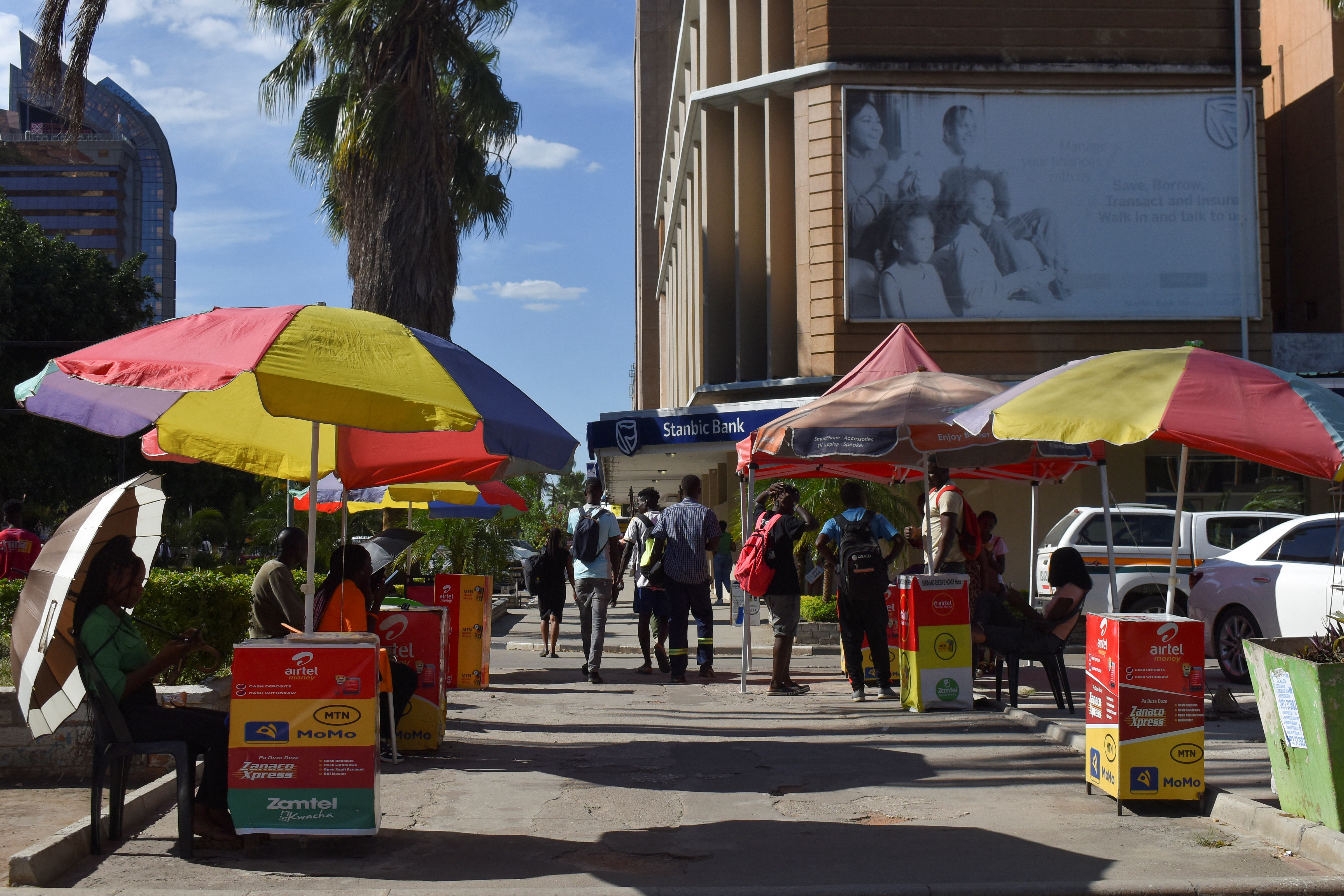 A line of mobile money agents sits at Lusaka's central business district