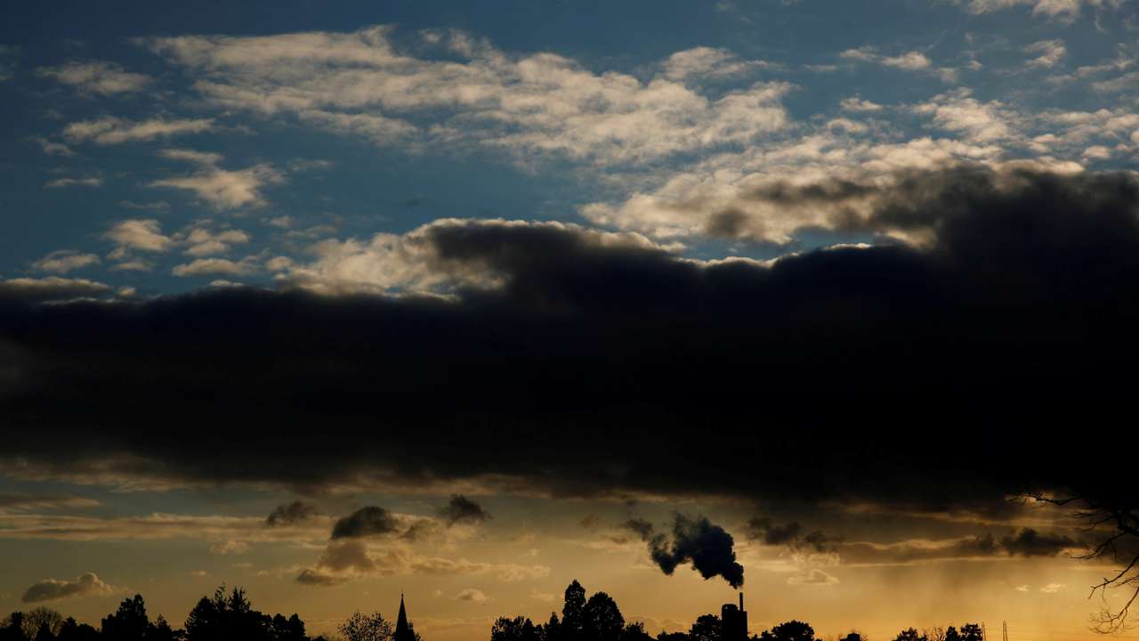 Smoke rises above a factory at sunset in Rugby