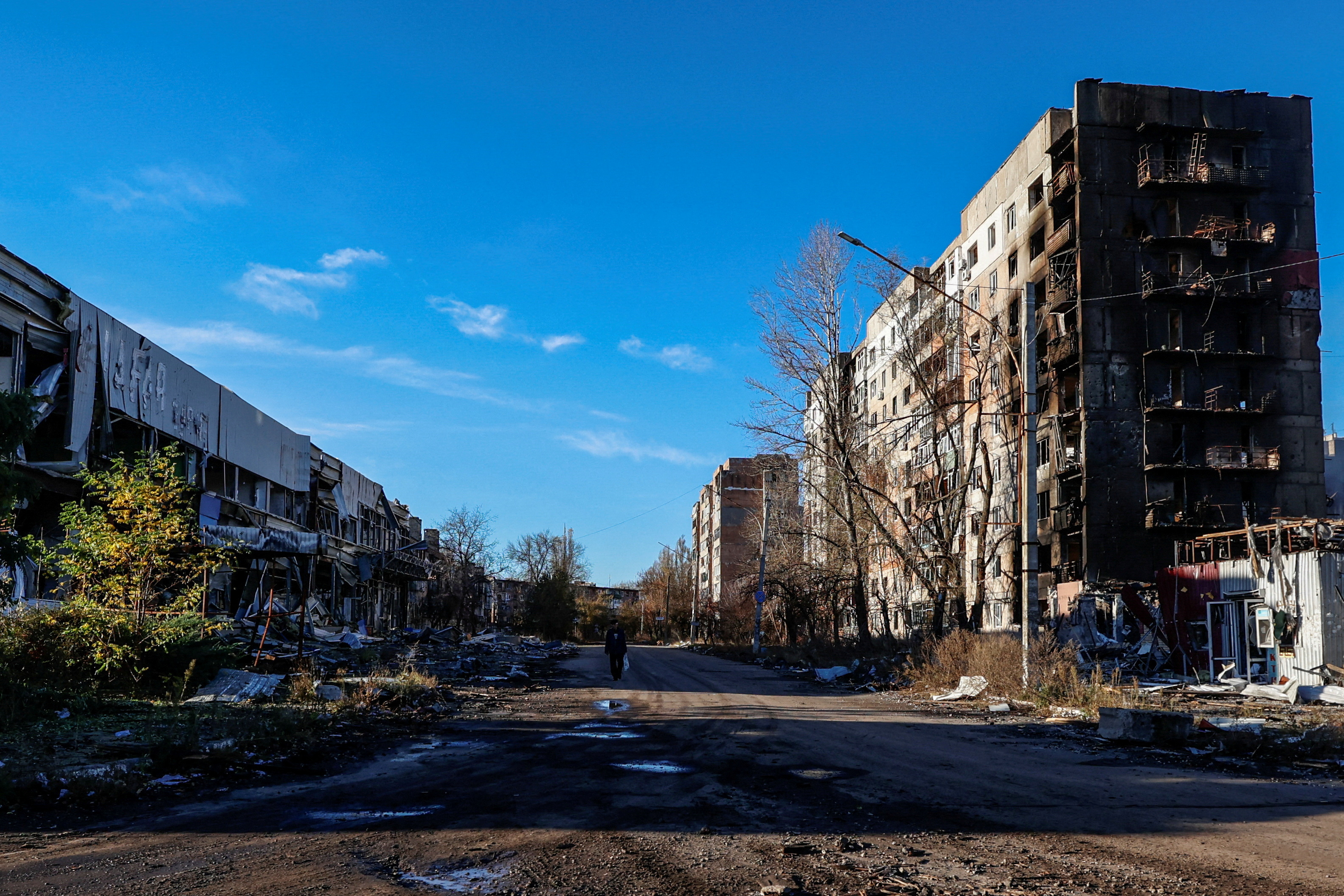 FILE PHOTO: Local resident walks next to residential buildings heavily damaged by permanent Russian military strikes in the front line town of Avdiivka