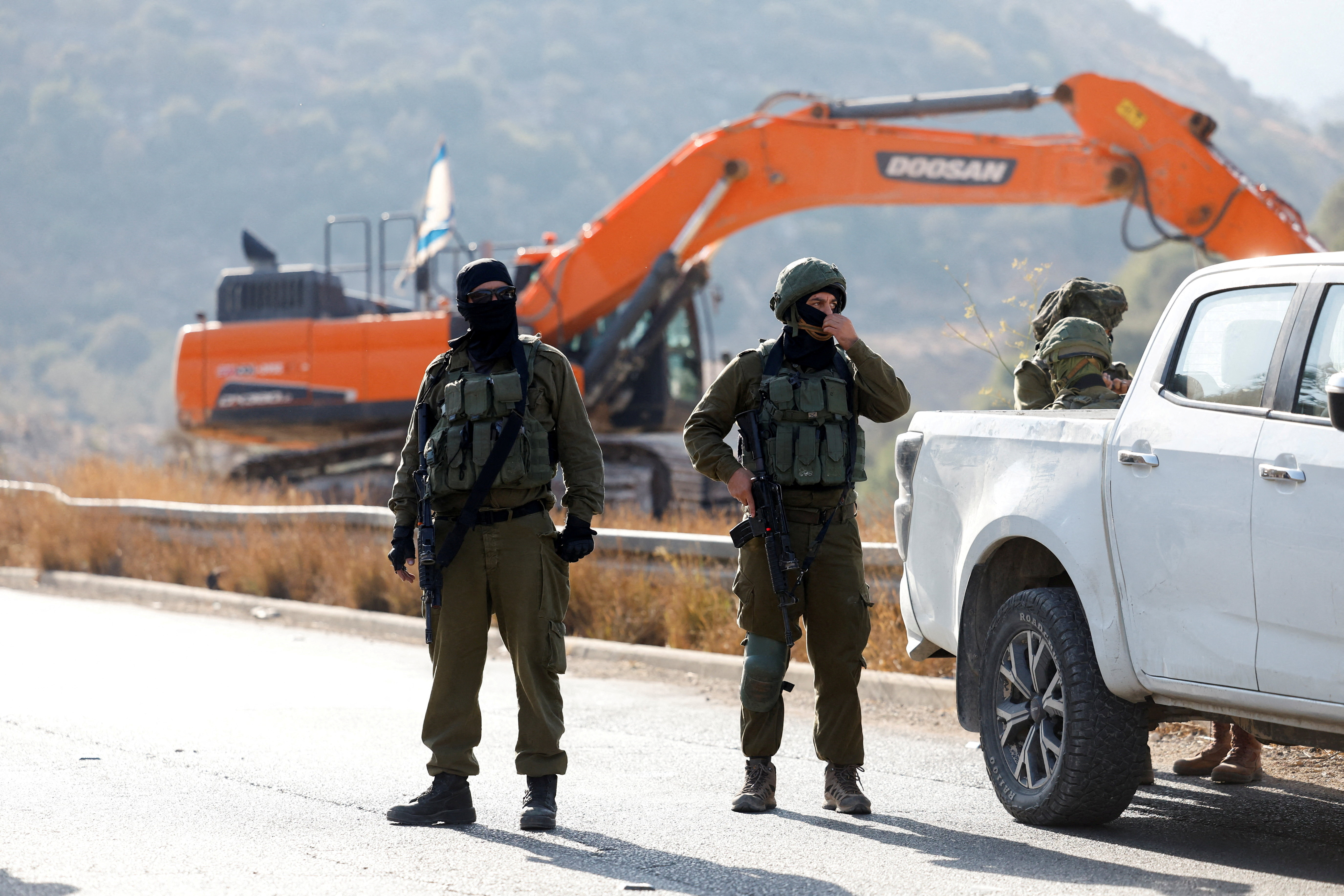 Israeli soldiers stand guard during the construction of Israeli bypass road infrastructure, near Ramallah