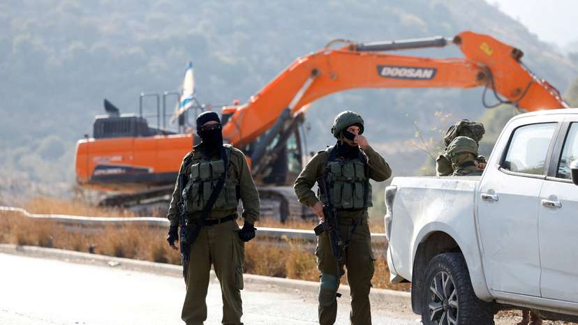 Israeli soldiers stand guard during the construction of Israeli bypass road infrastructure, near Ramallah