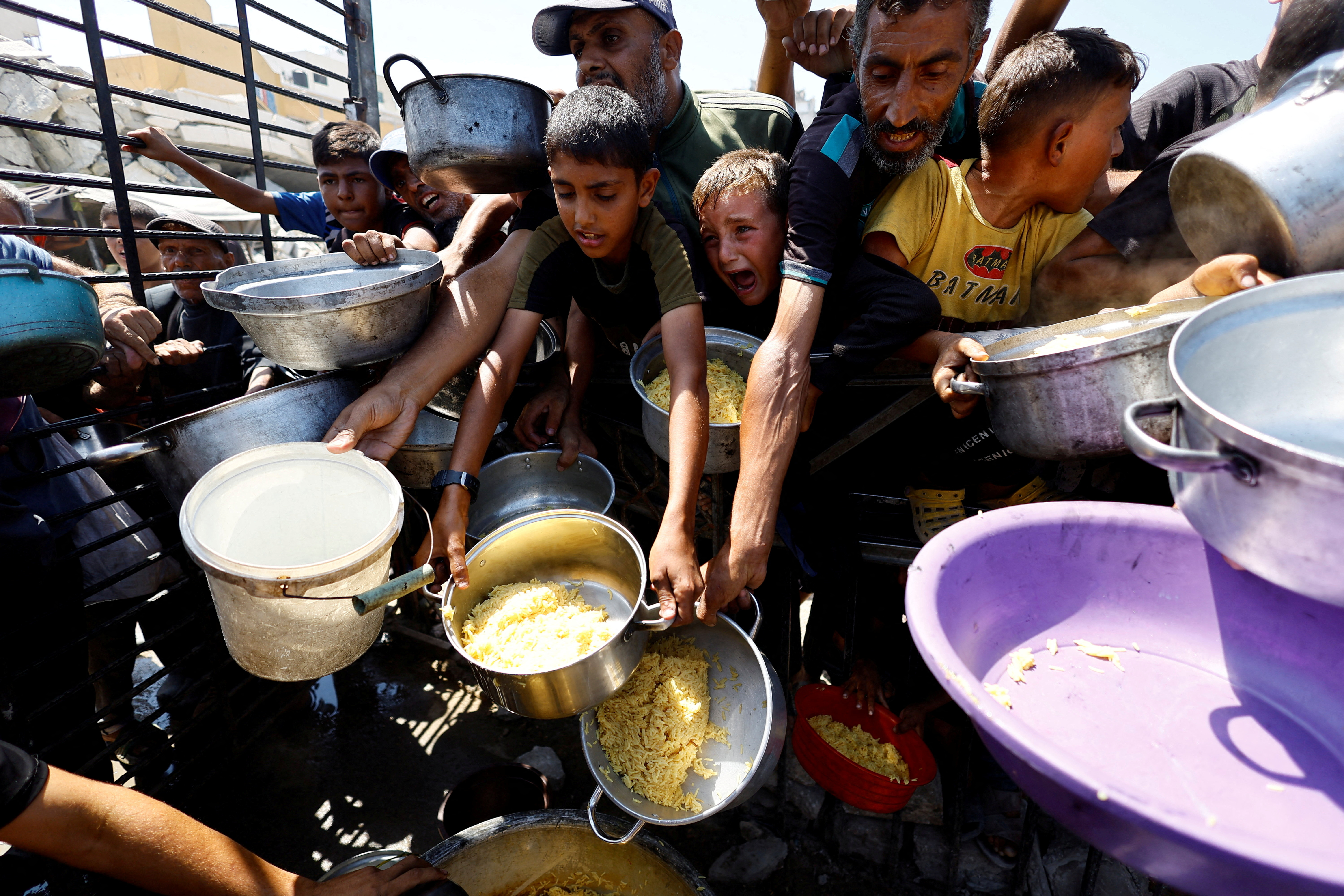 FILE PHOTO: Palestinians wait to receive food from a charity kitchen, in Gaza City