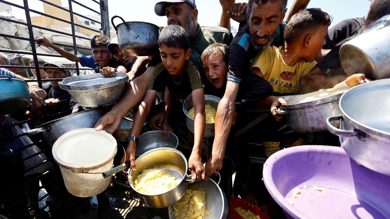 FILE PHOTO: Palestinians wait to receive food from a charity kitchen, in Gaza City