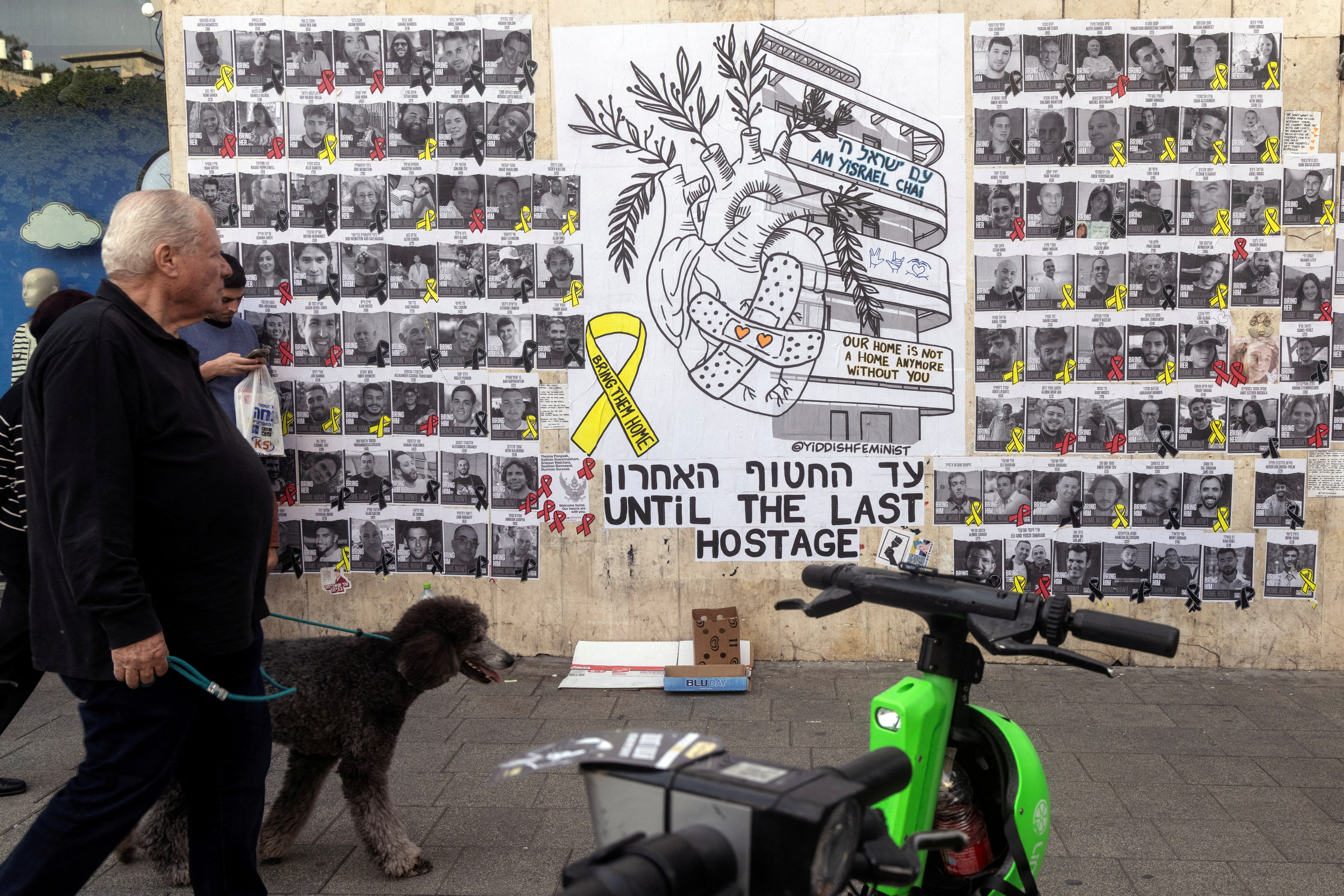 People walk next to a graffiti supporting the release of all hostages who have been held in Gaza since the deadly October 7, 2023 attack, in Tel Aviv