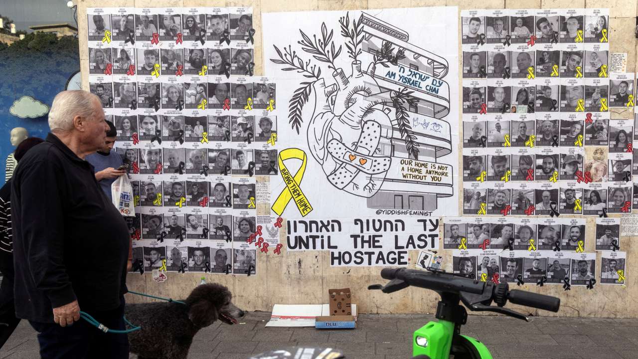 People walk next to a graffiti supporting the release of all hostages who have been held in Gaza since the deadly October 7, 2023 attack, in Tel Aviv