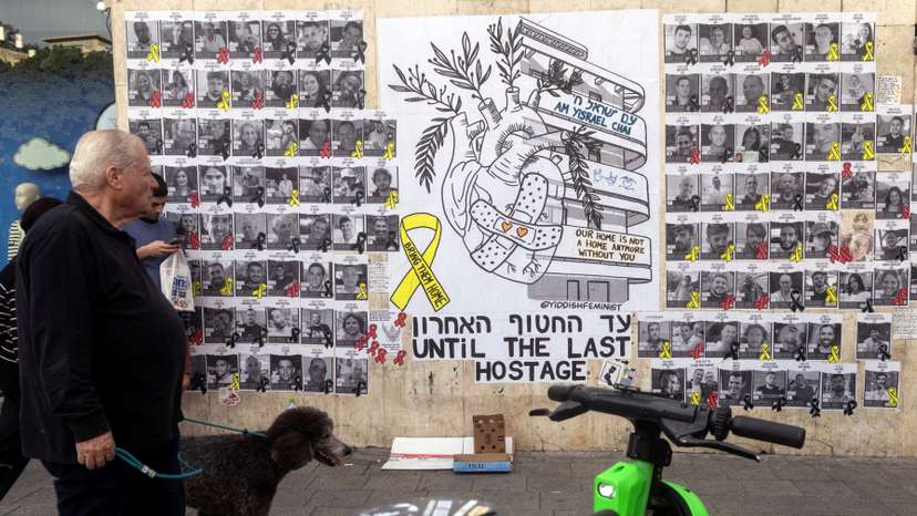 People walk next to a graffiti supporting the release of all hostages who have been held in Gaza since the deadly October 7, 2023 attack, in Tel Aviv