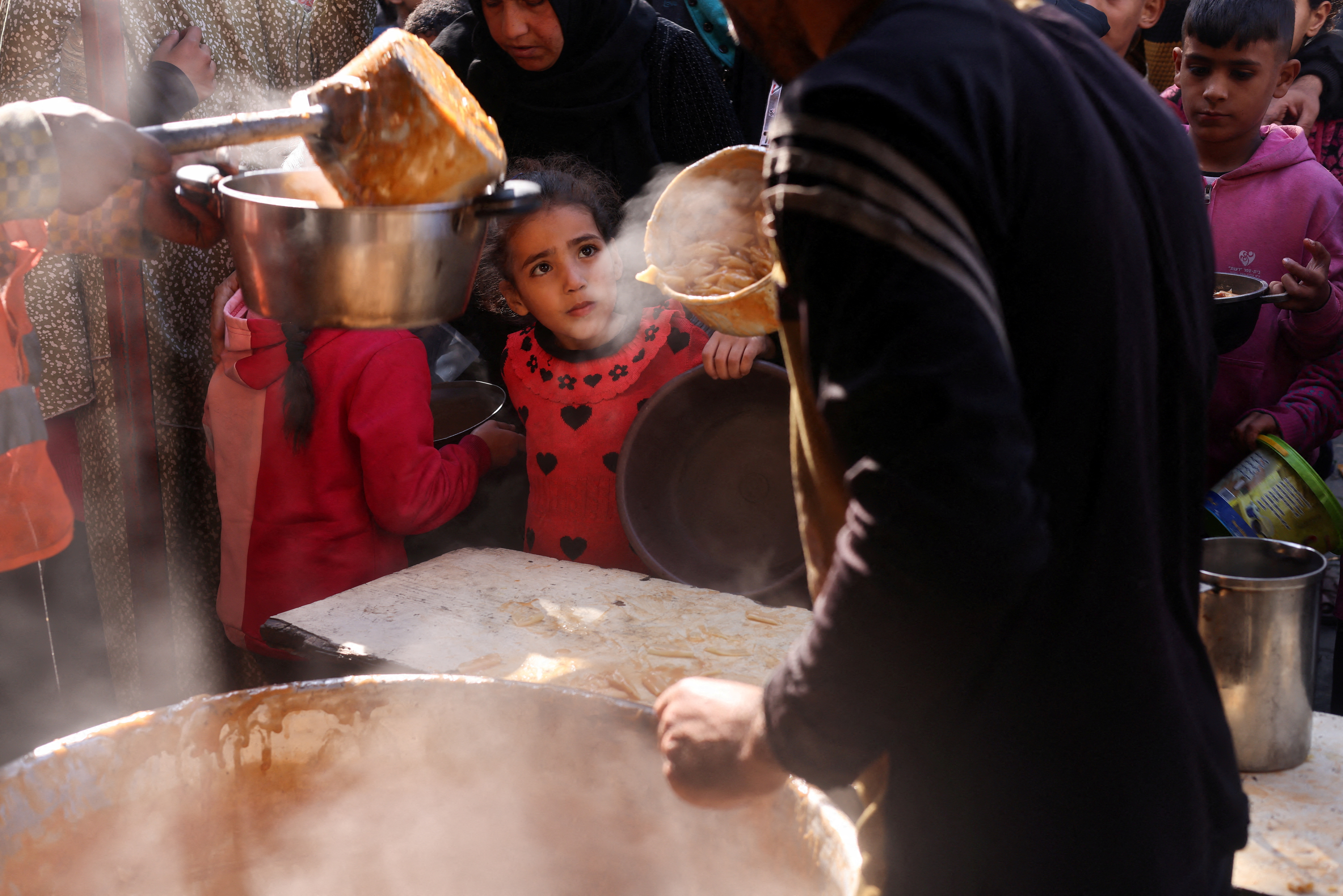 Palestinians wait to receive food amid shortages of food supplies, in Rafah in the southern Gaza Strip