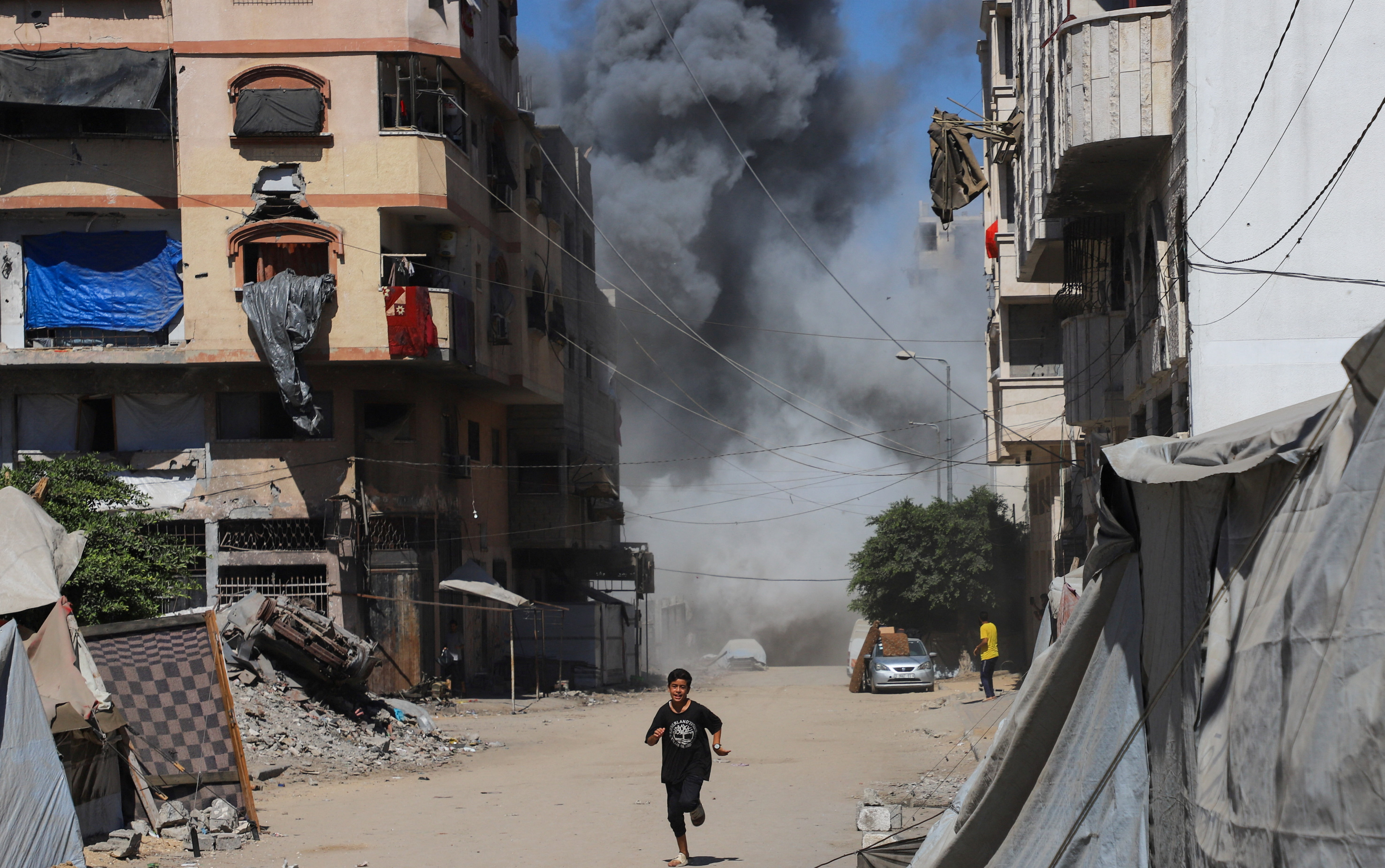 A boy runs as smoke rises from an evacuated residential building, which was housing displaced Palestinians, after it was hit by an Israeli air strike, in Gaza City