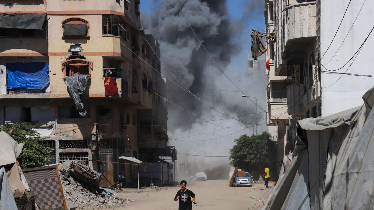 A boy runs as smoke rises from an evacuated residential building, which was housing displaced Palestinians, after it was hit by an Israeli air strike, in Gaza City