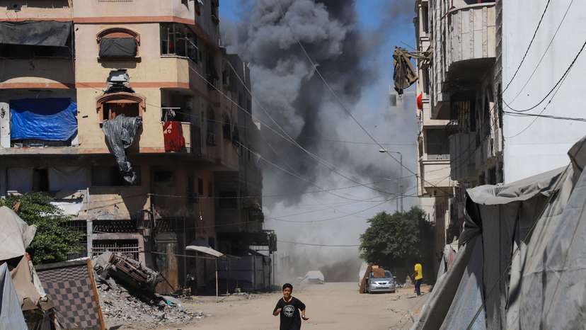 A boy runs as smoke rises from an evacuated residential building, which was housing displaced Palestinians, after it was hit by an Israeli air strike, in Gaza City