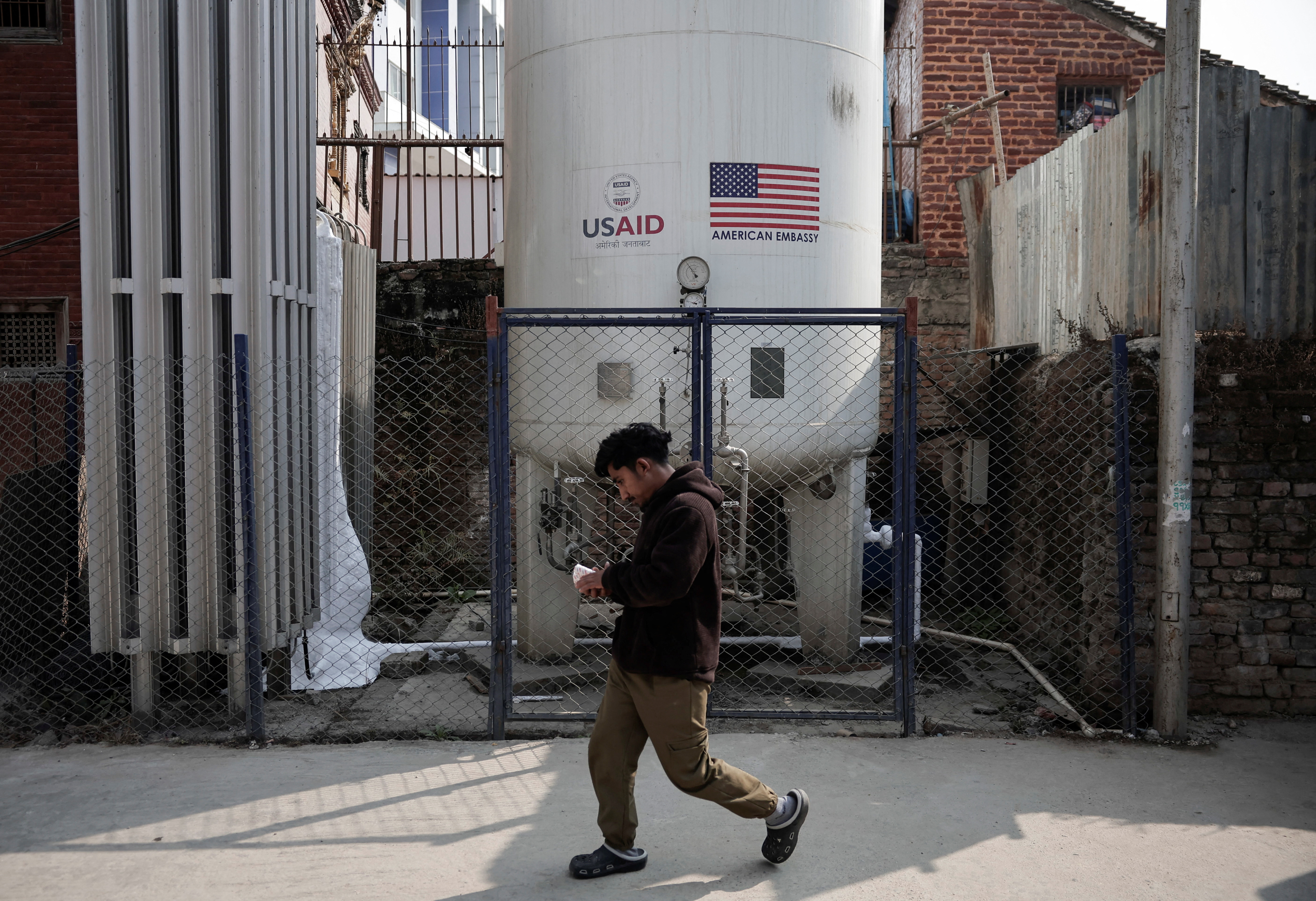 A man walks past the liquid oxygen storage tank installed at Bir Hospital by the United States Agency for International Development (USAID), in Kathmandu