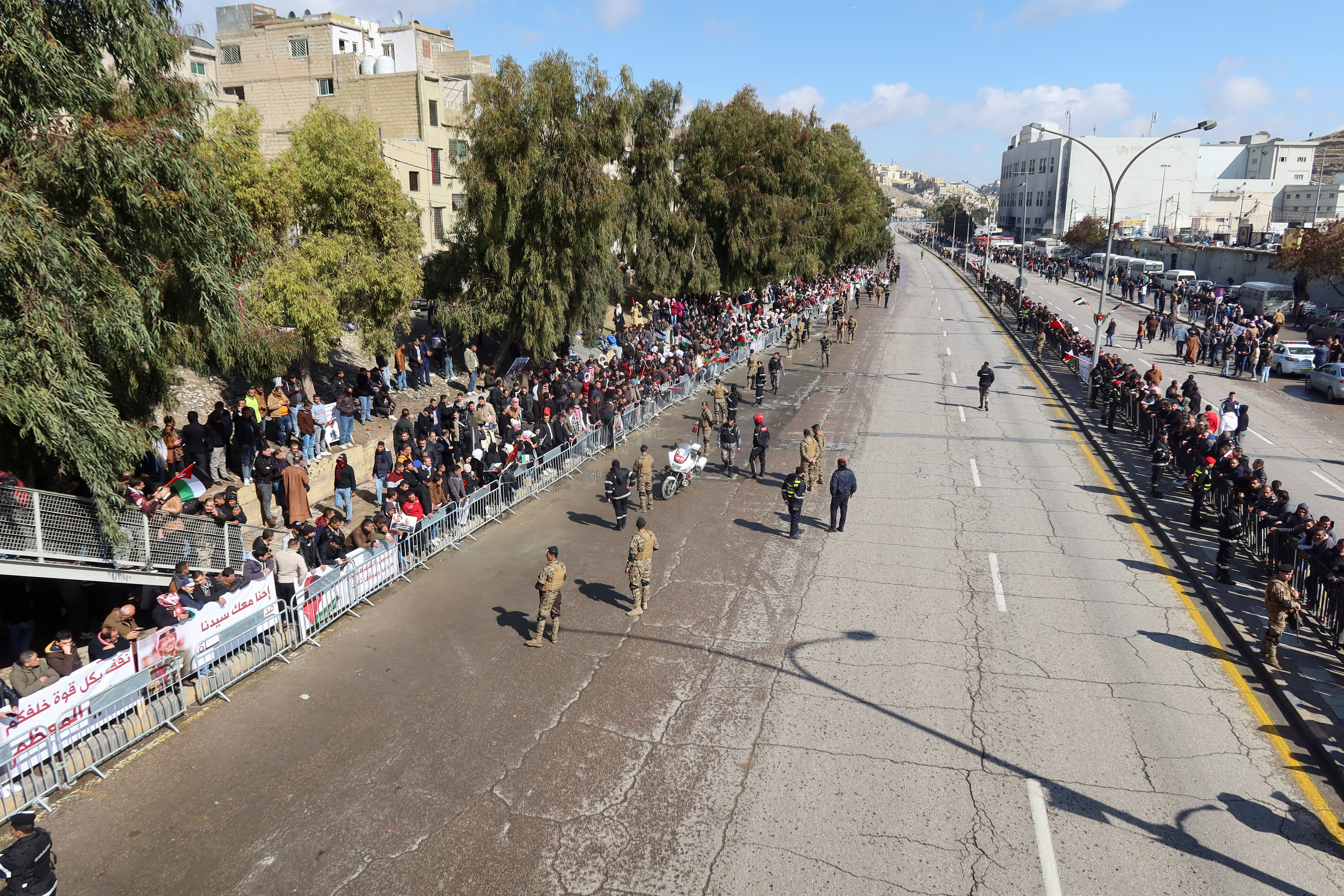 People gather along a road to welcome Jordan's King Abdullah upon his return from the U.S., in Amman