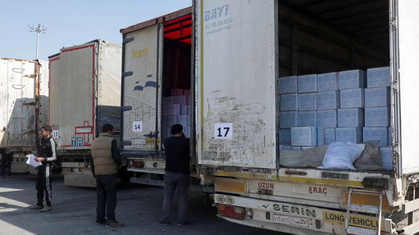 Men inspect aid trucks at Bab al-Hawa crossing
