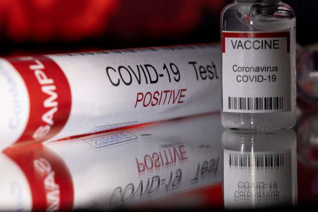 FILE PHOTO: Illustration shows a test tube labelled "COVID-19 Test positive" and a vial labelled "VACCINE Coronavirus COVID-19\