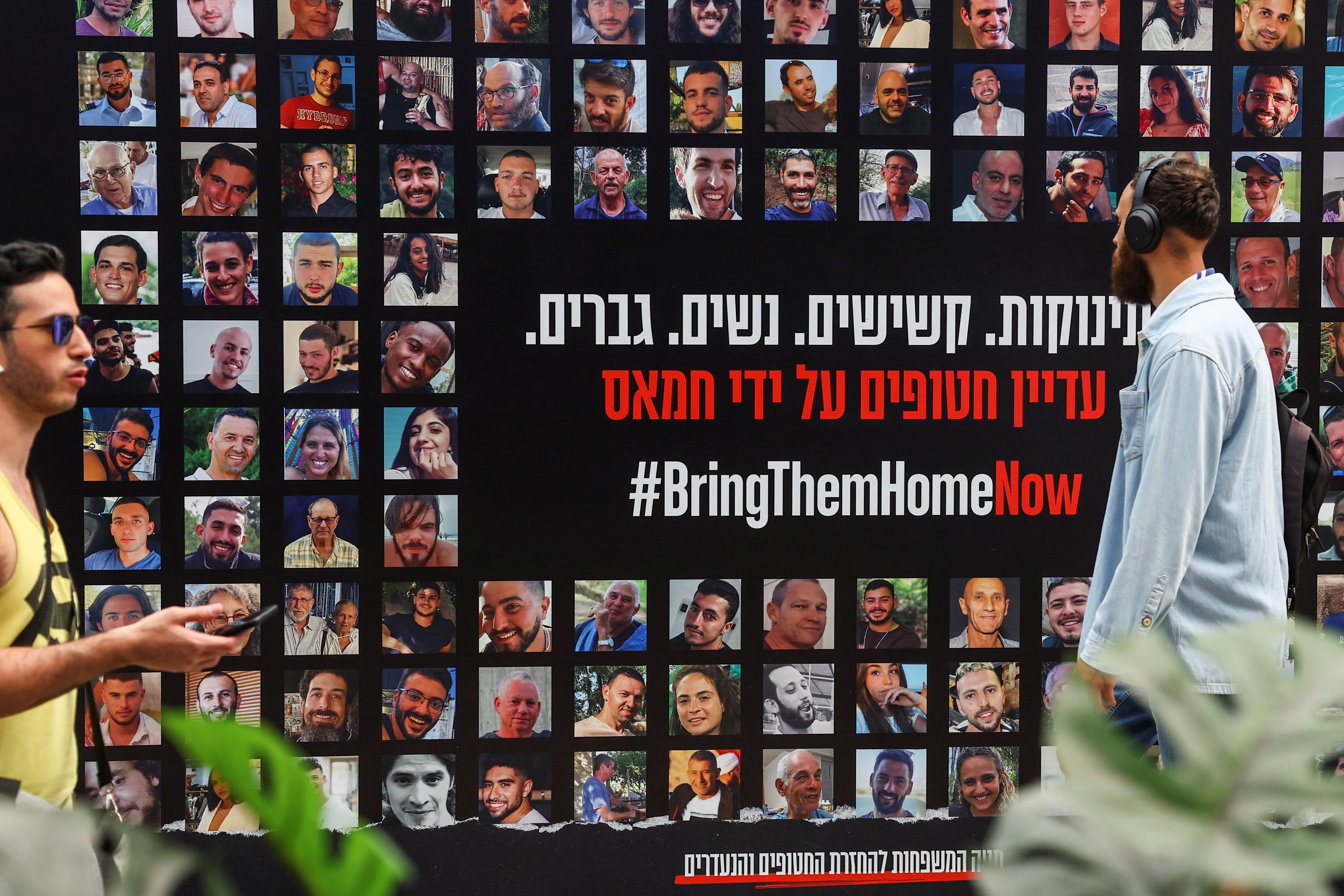 People walk past images of hostages kidnapped in the deadly October 7 attack on Israel by the Palestinian Islamist group Hamas from Gaza, in Tel Aviv