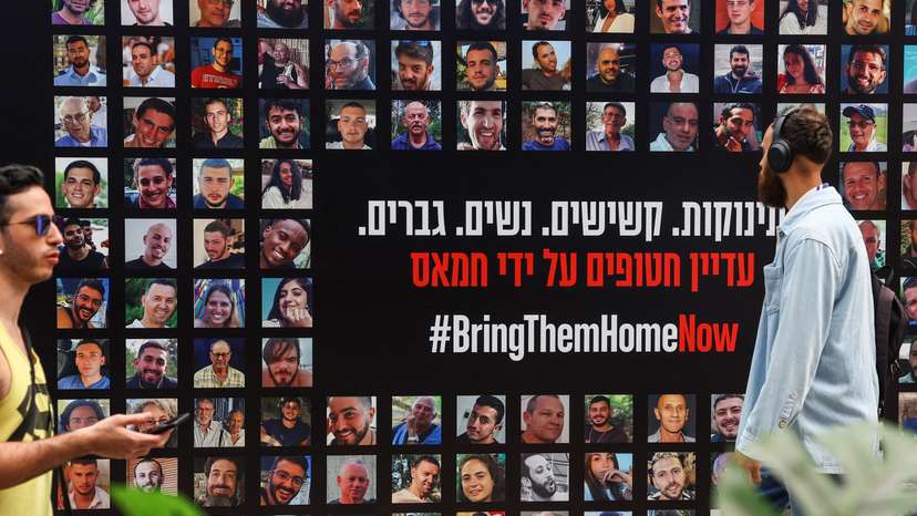 People walk past images of hostages kidnapped in the deadly October 7 attack on Israel by the Palestinian Islamist group Hamas from Gaza, in Tel Aviv
