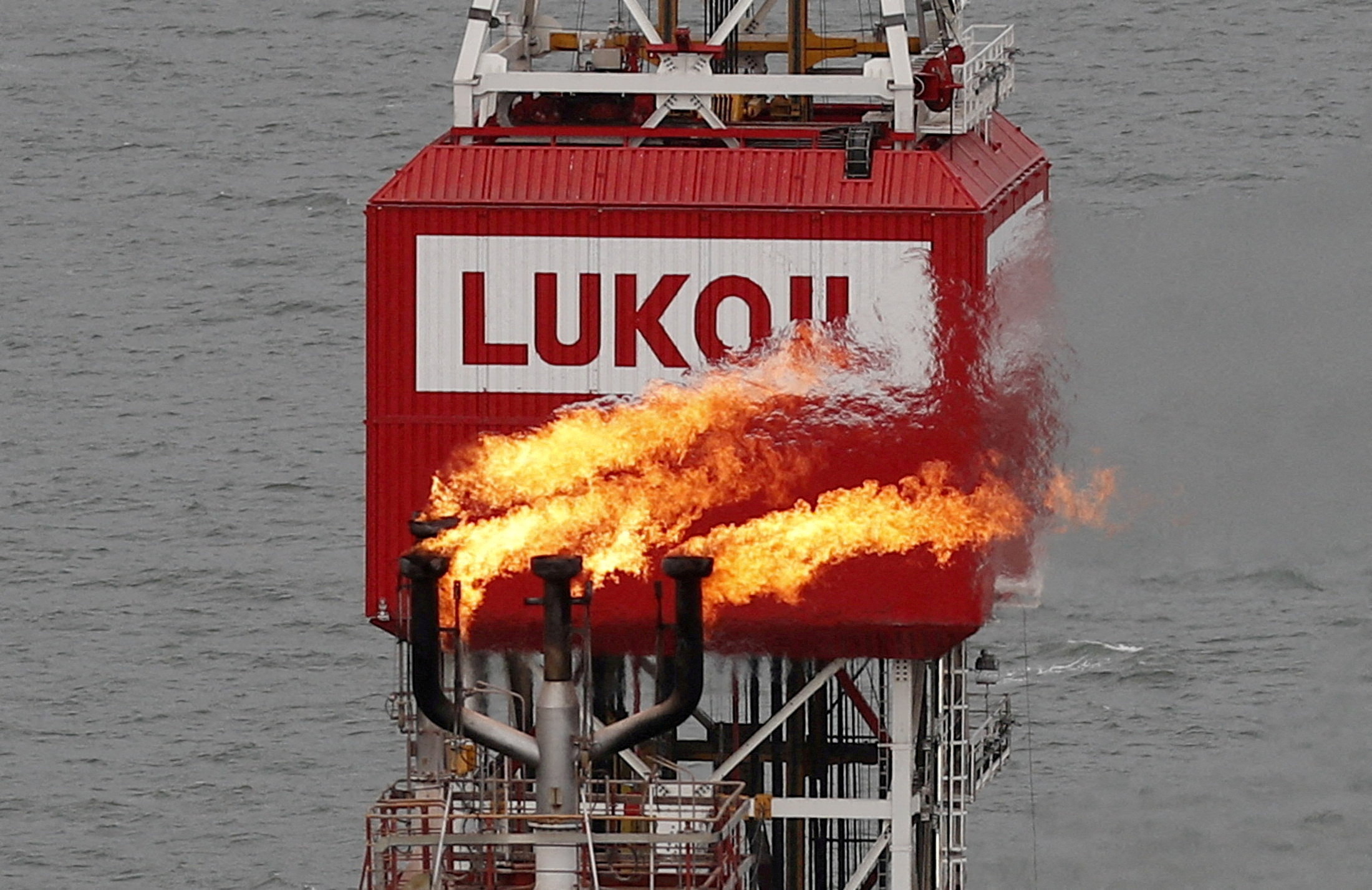 FILE PHOTO: A gas torch is seen next to the Lukoil company sign at the Filanovskogo oil platform in the Caspian Sea