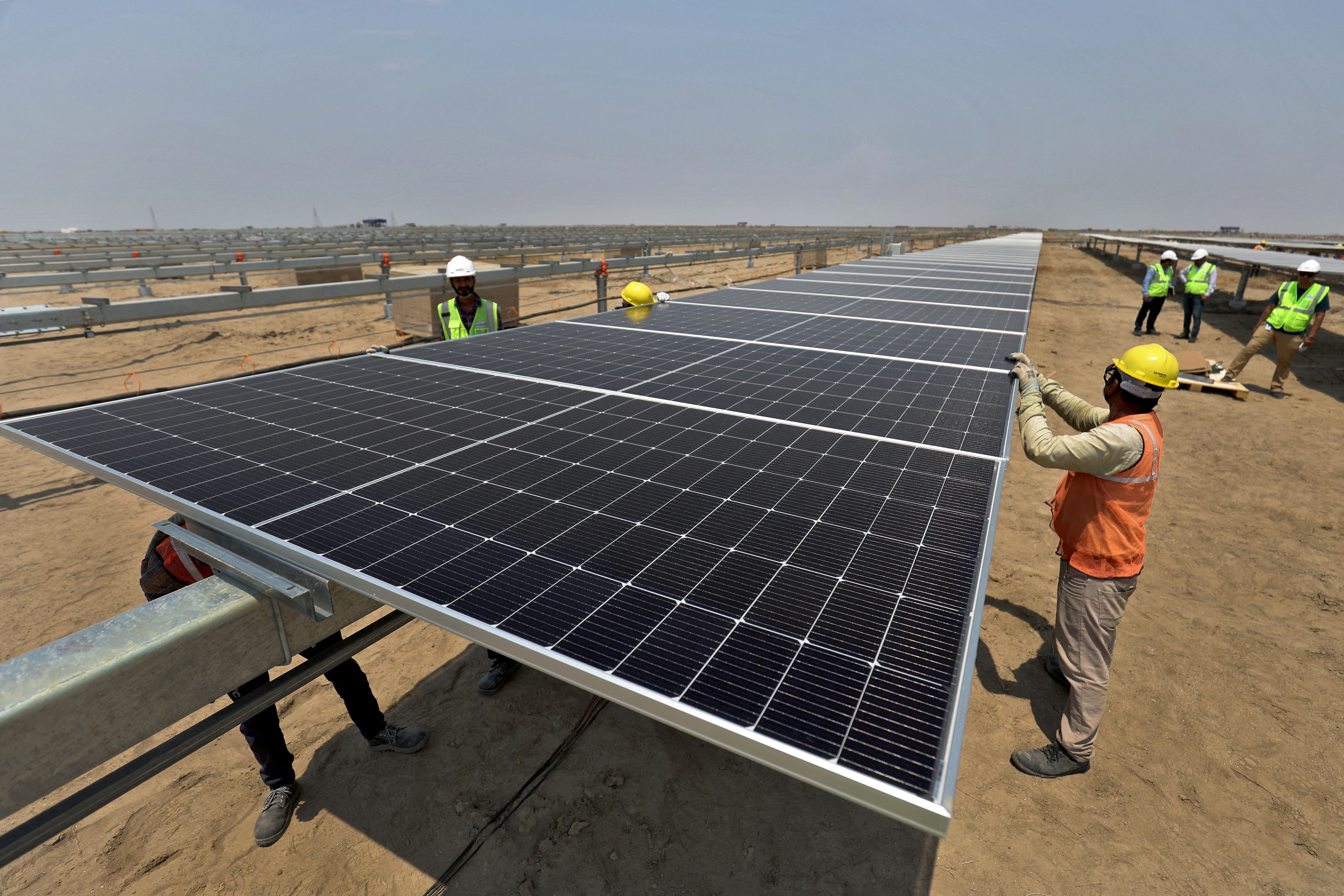 FILE PHOTO: Workers install solar panels at the Khavda Renewable Energy Park of Adani Green Energy Ltd (AGEL)  in Khavda