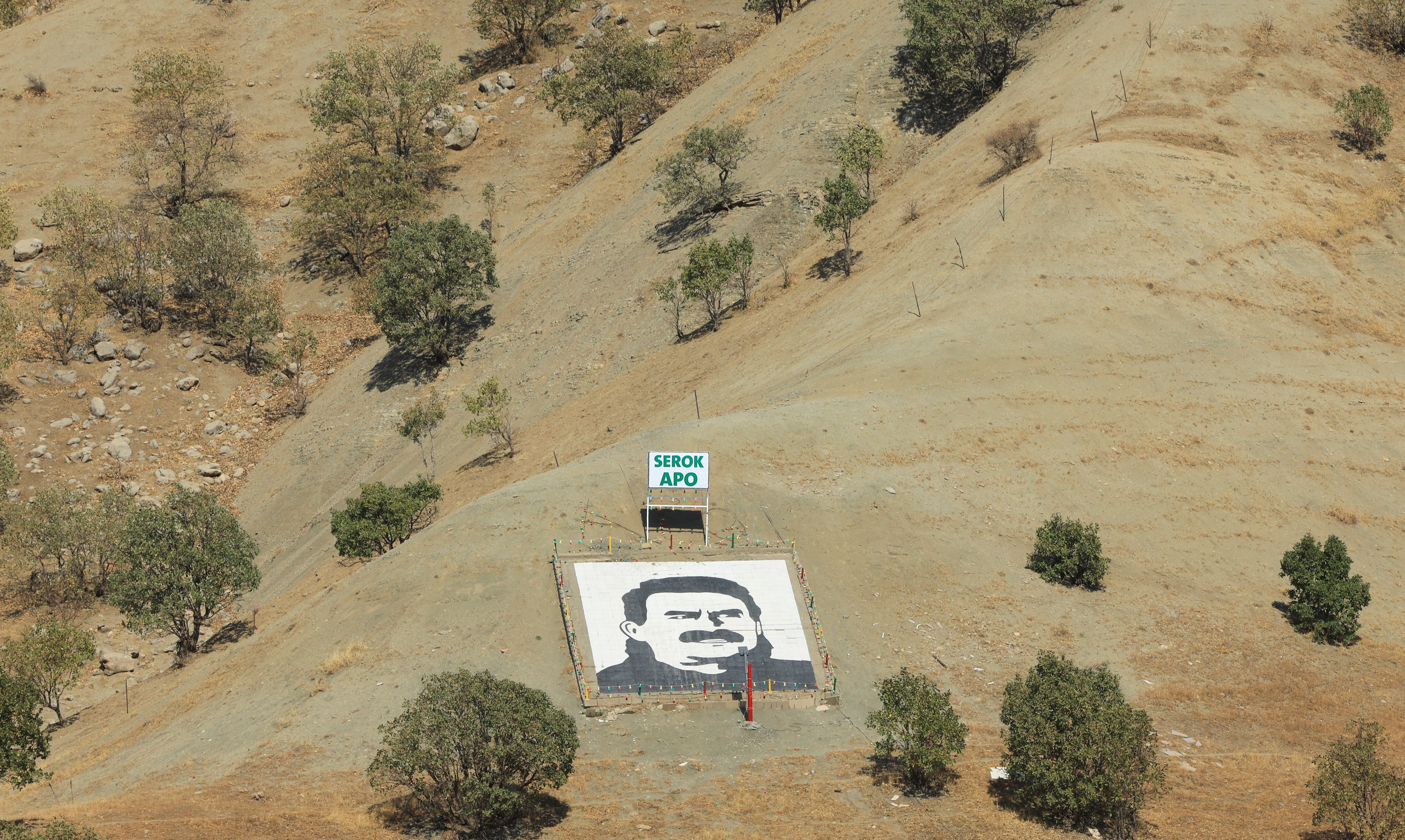 A portrait of jailed Kurdistan Workers Party leader Abdullah Ocalan and a sign with the words "Serok Apo," are displayed on a hillside in the Qandil mountains