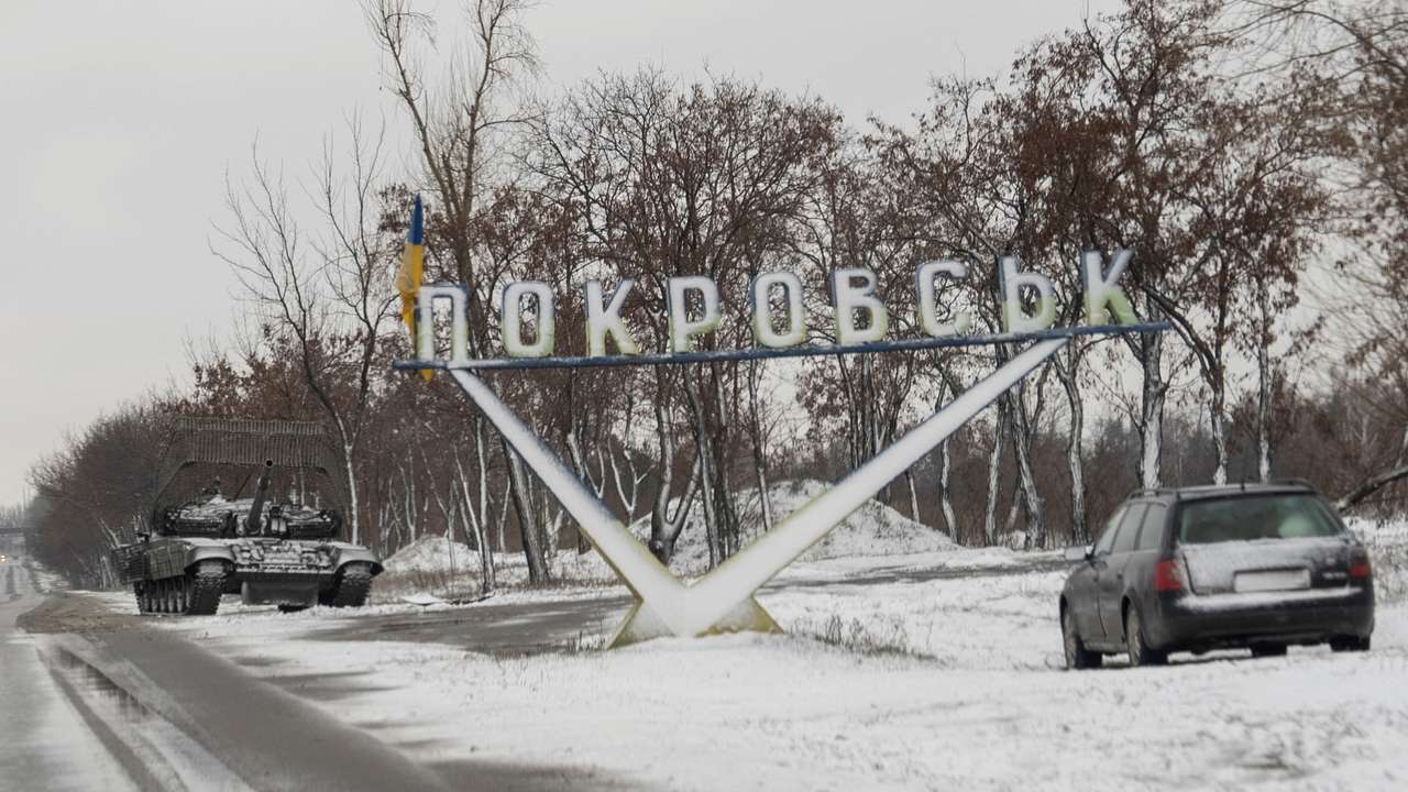FILE PHOTO: A Ukrainian tank and a car are parked near a road sign that reads, 'Pokrovsk’ in the town of Pokrovsk