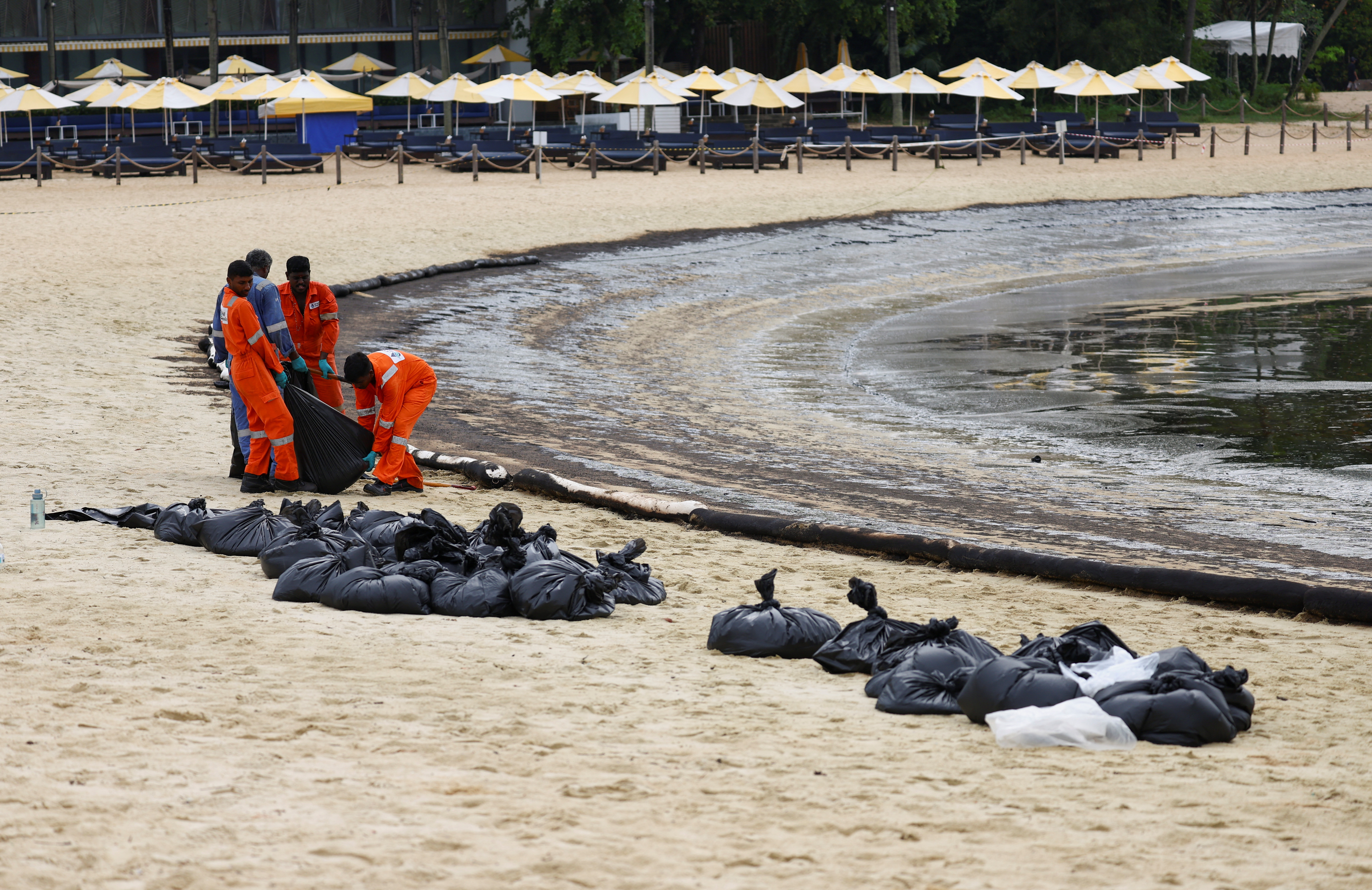 Workers clean up the oil slick at Tanjong Beach in Sentosa