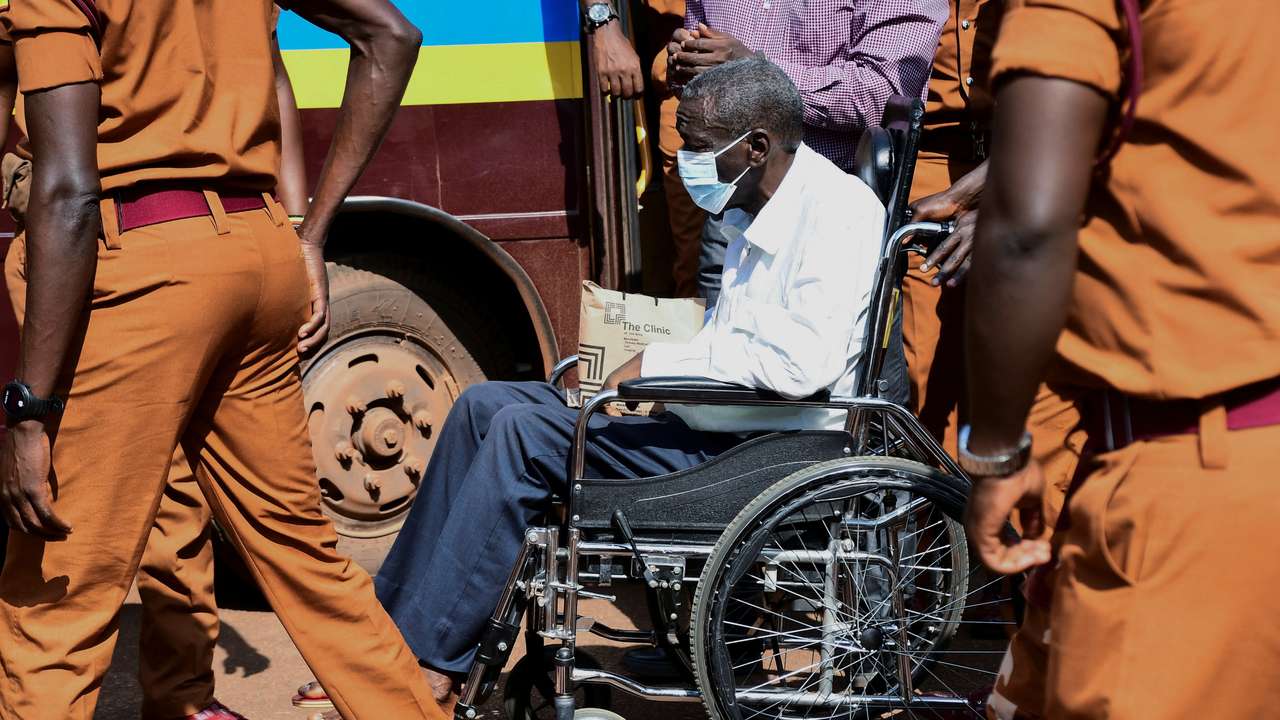 Prison warders wheel Uganda's four-time presidential candidate Kizza Besigye to the Chief Magistrate Court in Nakawa suburb of Kampala