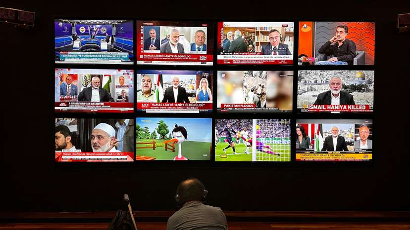 A person watches the news on multiple TV screens, most of them announcing the killing of senior Hamas leader Ismail Haniyeh