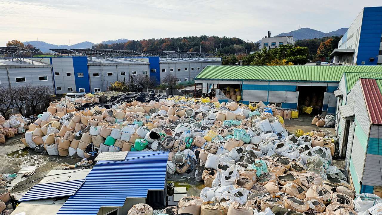 A pile of untreated, shredded plastic waste is left unattended at an inoperational recycling site in Asan