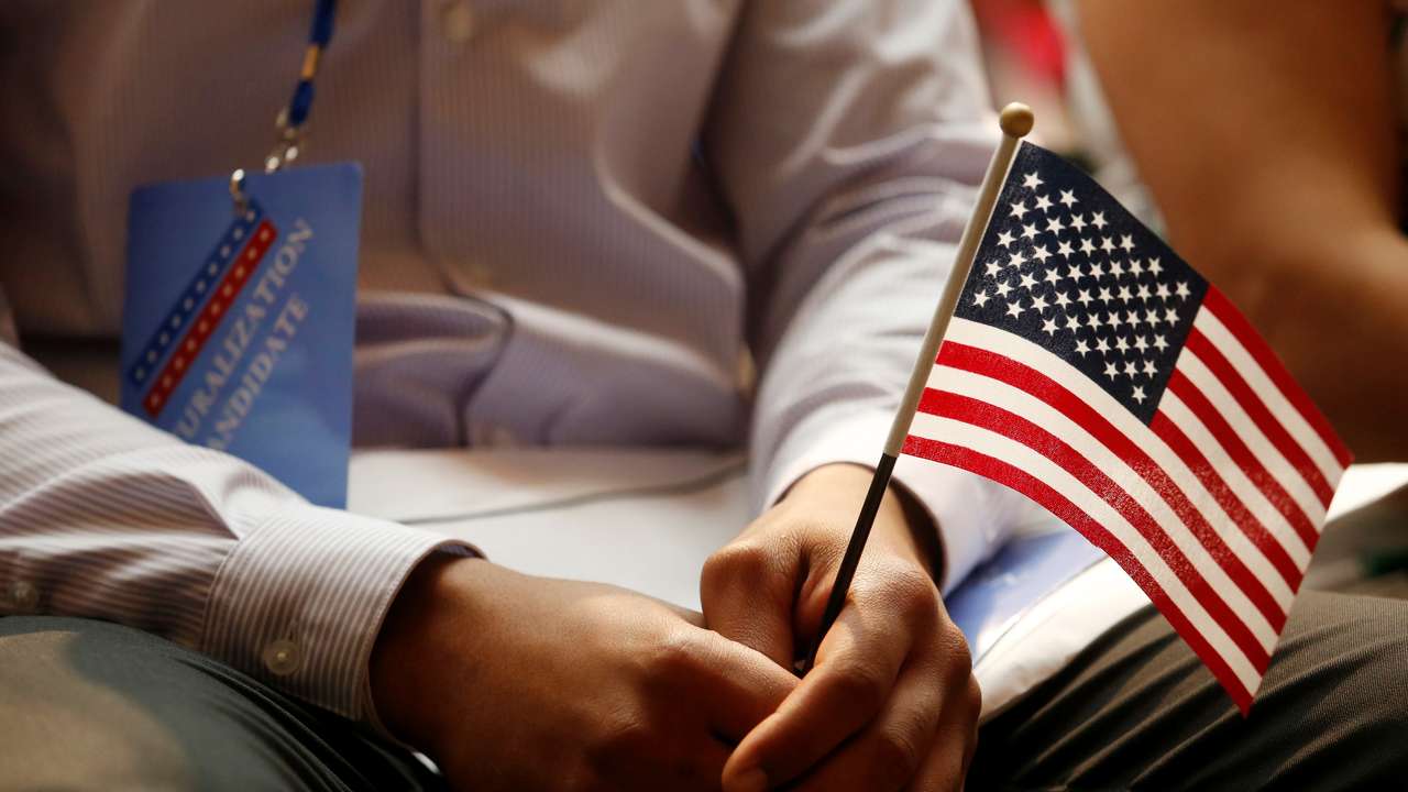 A new citizen holds a U.S. flag at the U.S. Citizenship and Immigration Services (USCIS) naturalization ceremony at the New York Public Library in Manhattan