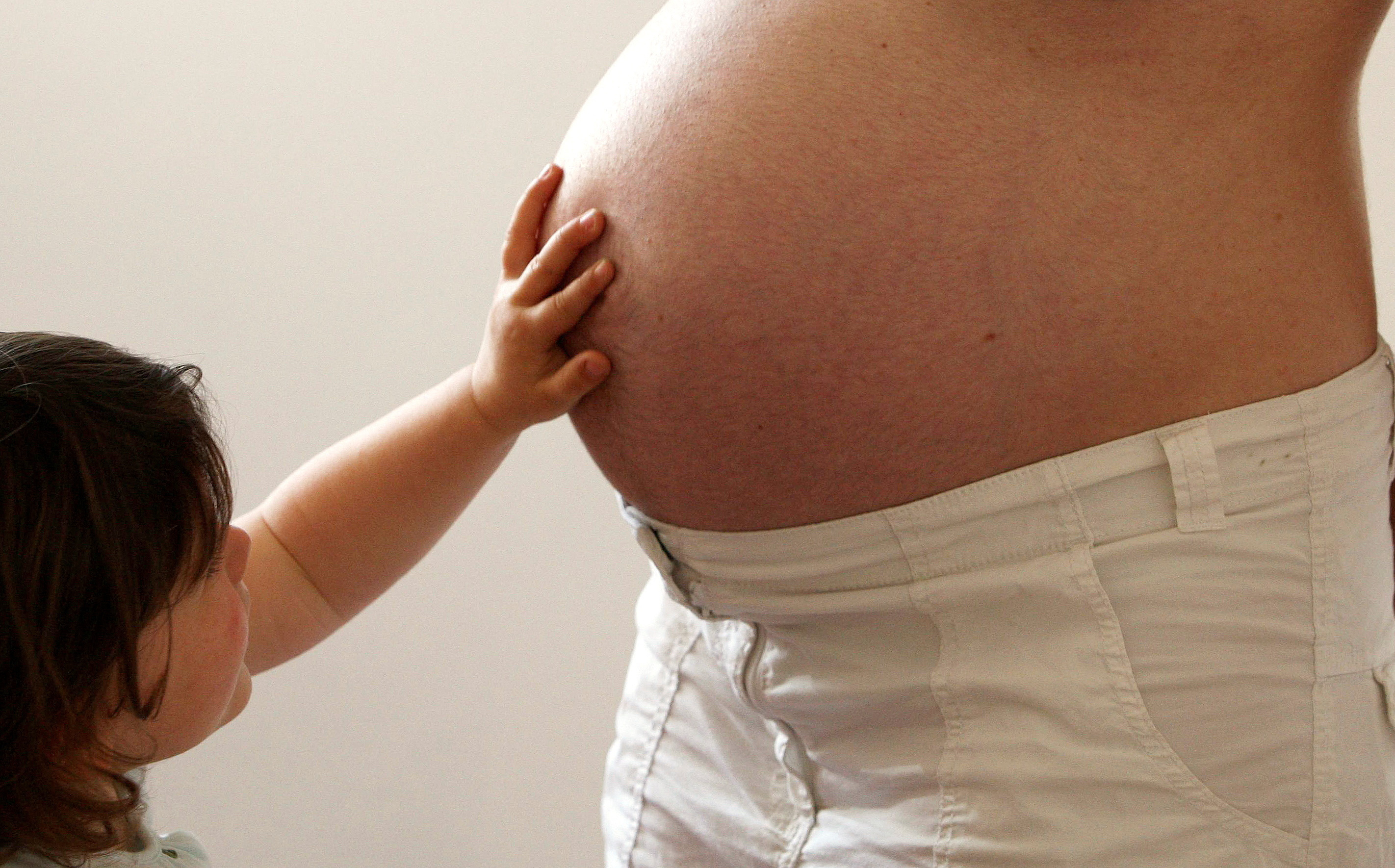 FILE PHOTO: A child touches her pregnant mother's stomach at the last stages of her pregnancy in Bordeaux