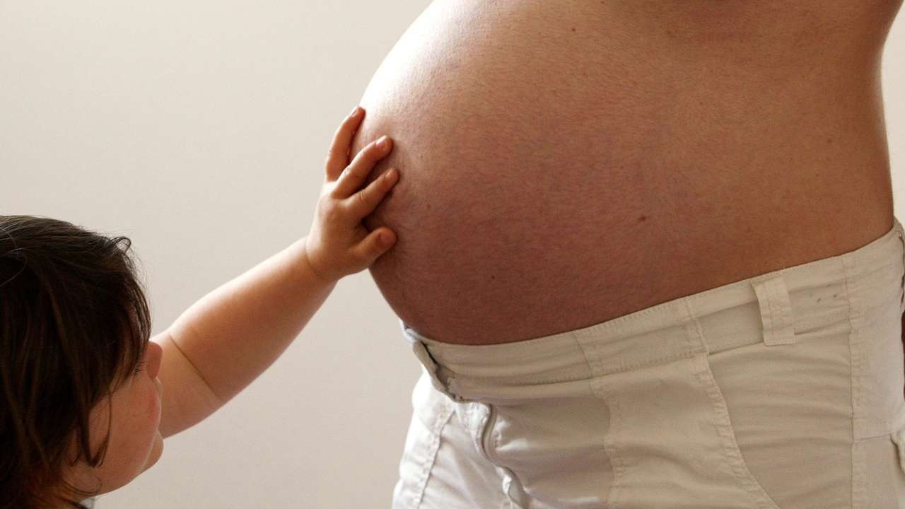 FILE PHOTO: A child touches her pregnant mother's stomach at the last stages of her pregnancy in Bordeaux