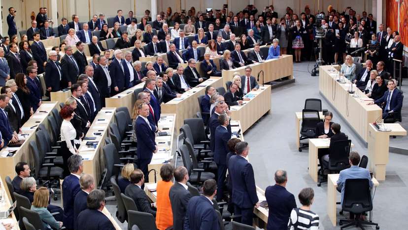 Members of the Parliament stand during a session of the Parliament in Vienna