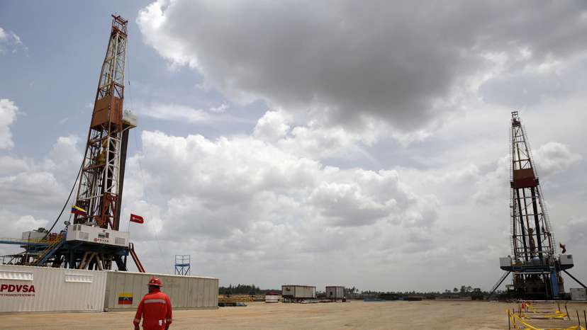 FILE PHOTO: An oilfield worker walks next to drilling rigs at an oil well operated by Venezuela's state oil company PDVSA, in the oil rich Orinoco belt, near Morichal at the state of Monagas