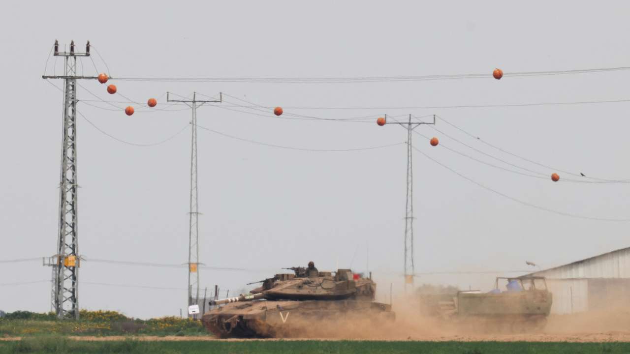 An Israeli tank pulls an armoured personnel carrier (APC) near the Israel-Gaza border, amid the ongoing conflict between Israel and the Palestinian Islamist group Hamas, as seen from Israel