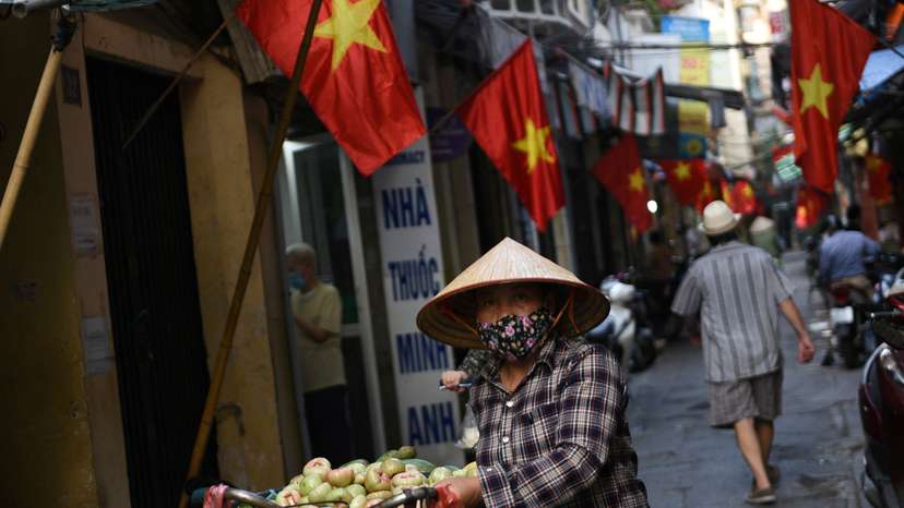 A vendor walks in an alley decorated with national flags ahead of the upcoming elections in Hanoi