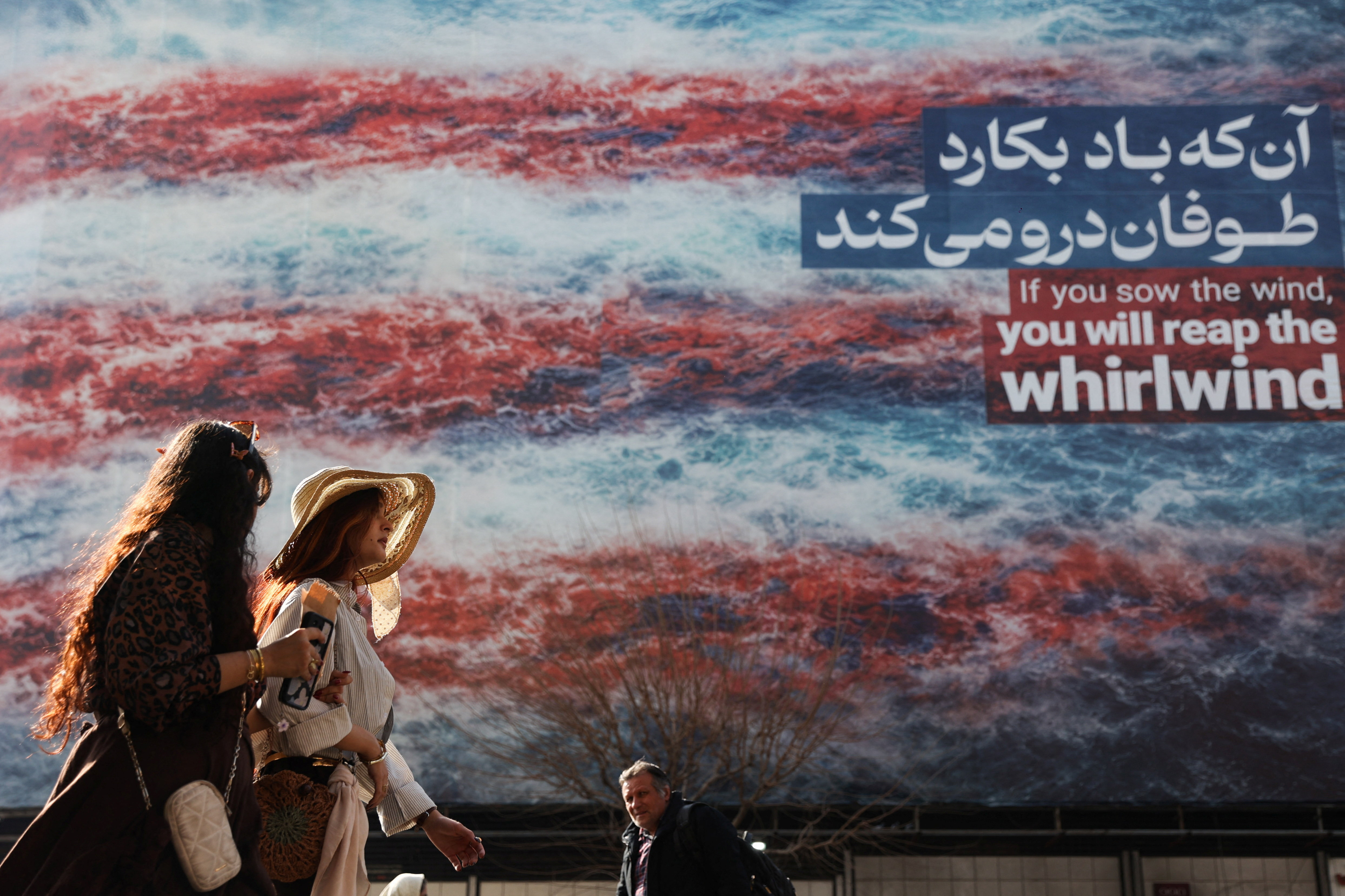 Iranian women walk past an anti-U.S. billboard in Tehran