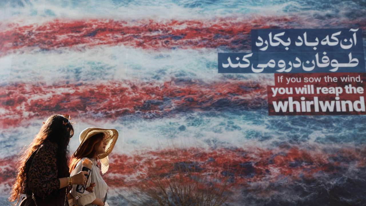 Iranian women walk past an anti-U.S. billboard in Tehran