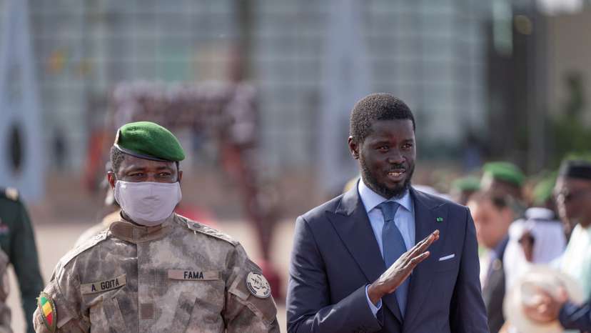 Senegal's President Bassirou Diomaye Faye waves as he walks along with Mali's junta leader Assimi Goita in Bamako