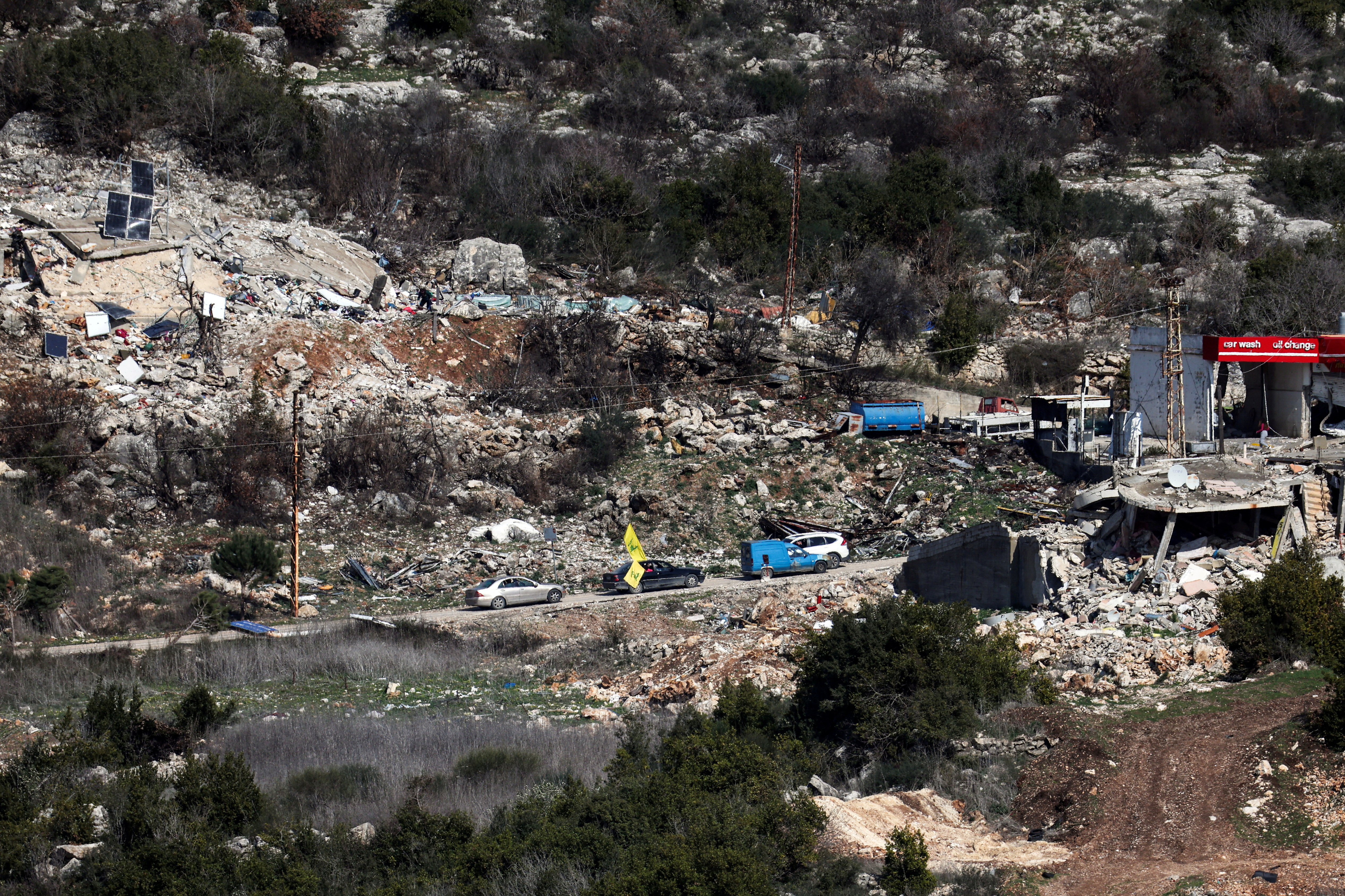 Lebanese vehicles drive past damaged buildings in southern Lebanon, as seen from northern Israel, after a ceasefire between Israel and Hezbollah took effect