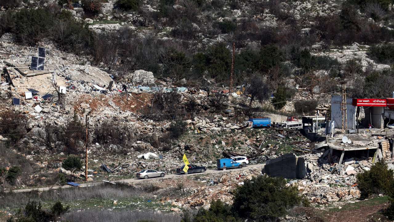Lebanese vehicles drive past damaged buildings in southern Lebanon, as seen from northern Israel, after a ceasefire between Israel and Hezbollah took effect