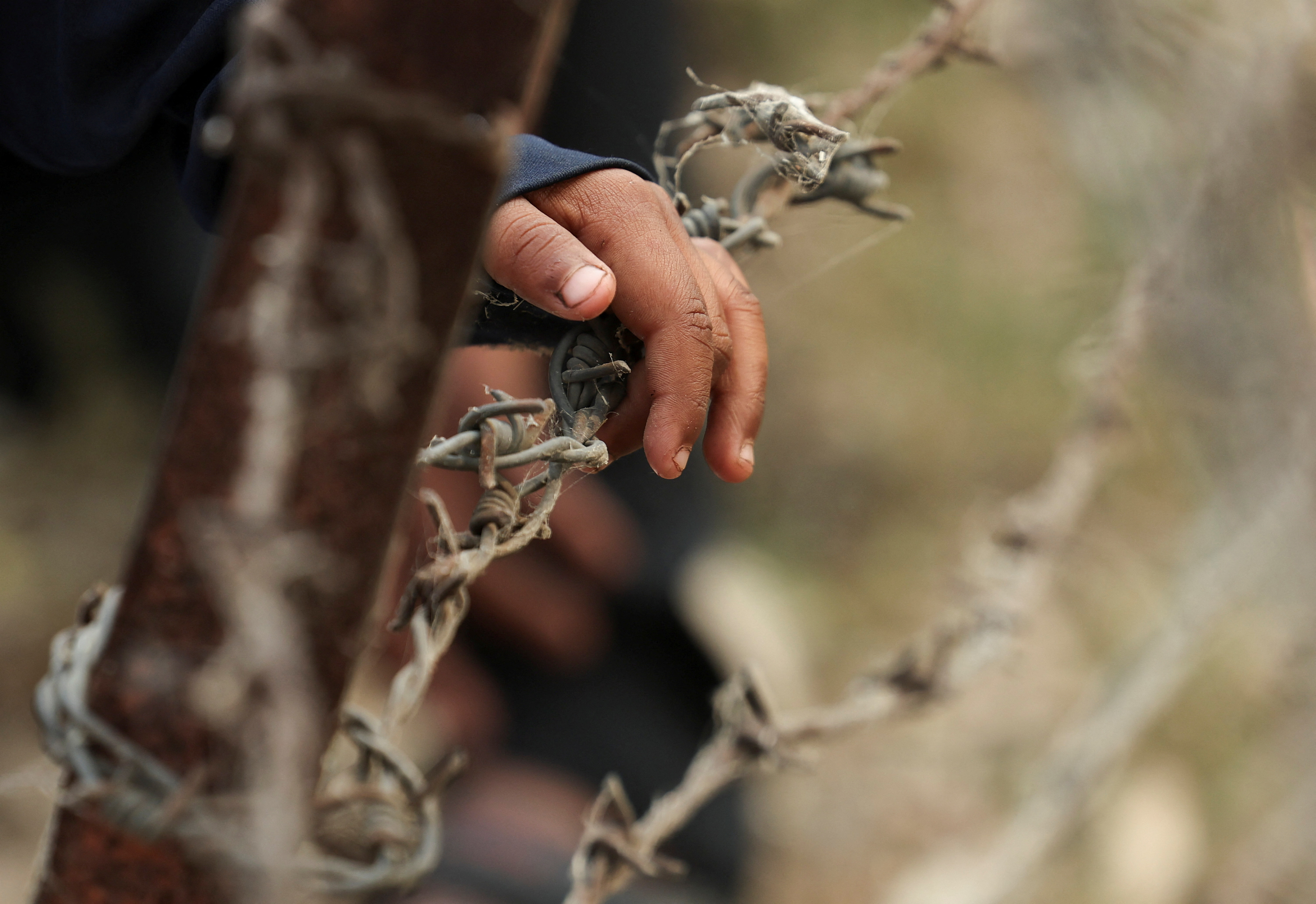 A child from Pakistan places his hand on barbed wire as he waits to go to Pakistan at the Attari-Wagah border crossing, near Amritsar