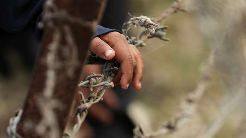 A child from Pakistan places his hand on barbed wire as he waits to go to Pakistan at the Attari-Wagah border crossing, near Amritsar