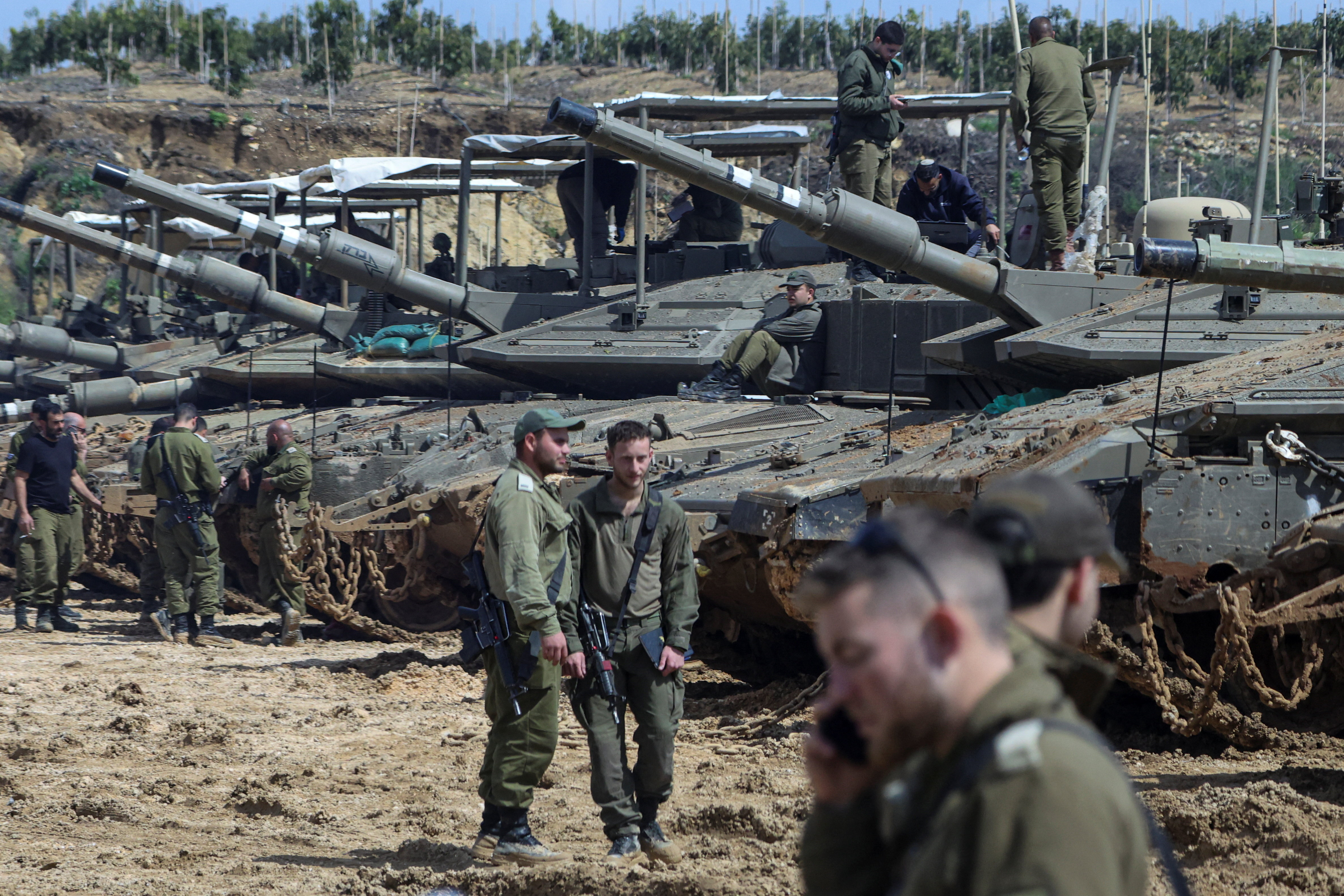 Israeli soldiers stand next to tanks near the Israeli side of the border with Lebanon in northern Israel